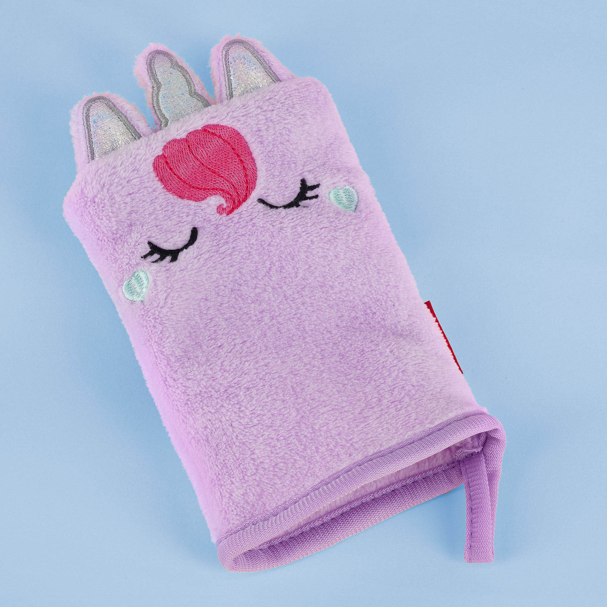 Lilafarbener Abschminkhandschuh im Einhorn-Design, flach auf einer einfarbigen Fläche dargestellt.