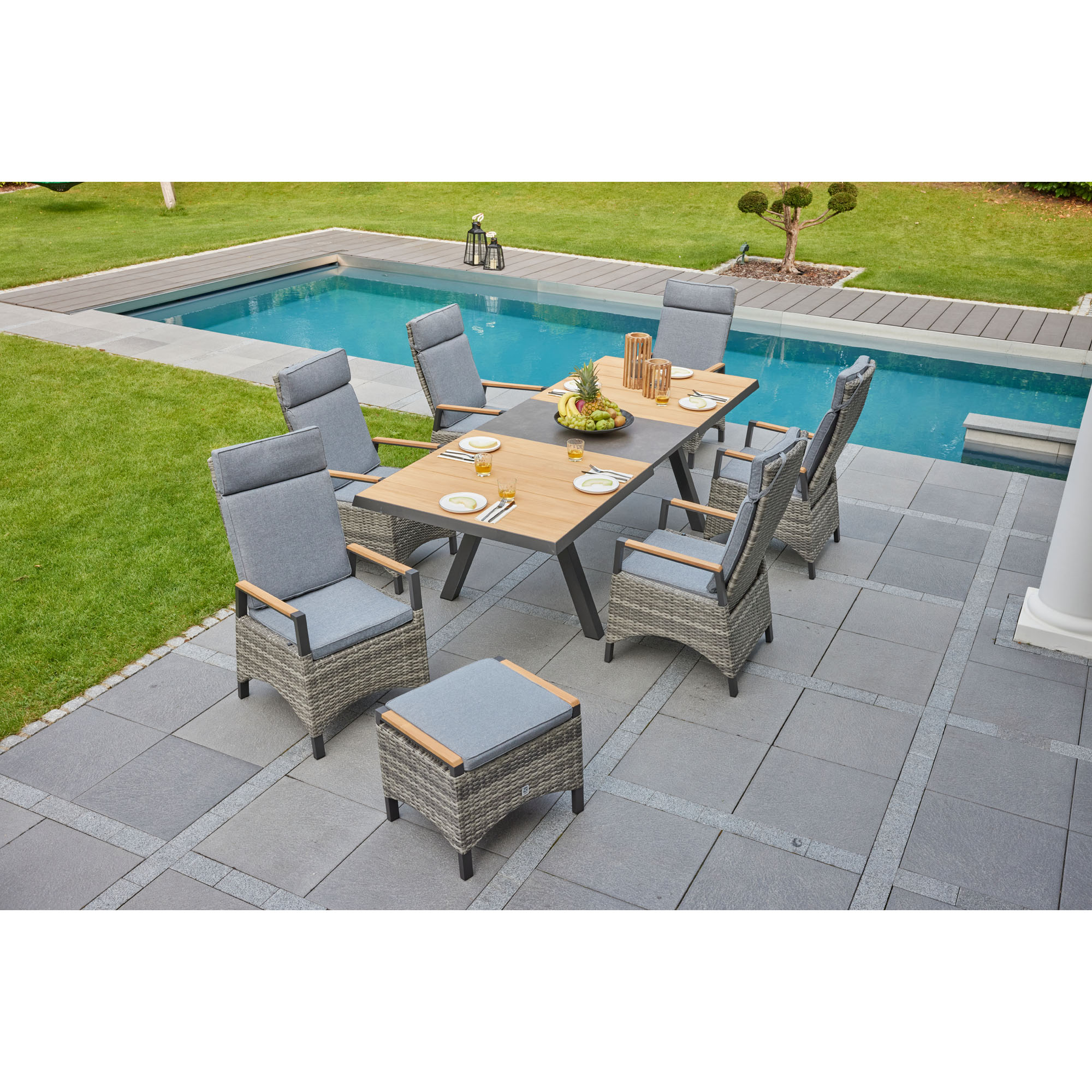 Mehrere Gartenstühle mit Polstern stehen um einen Tisch auf einer Terrasse neben einem Pool