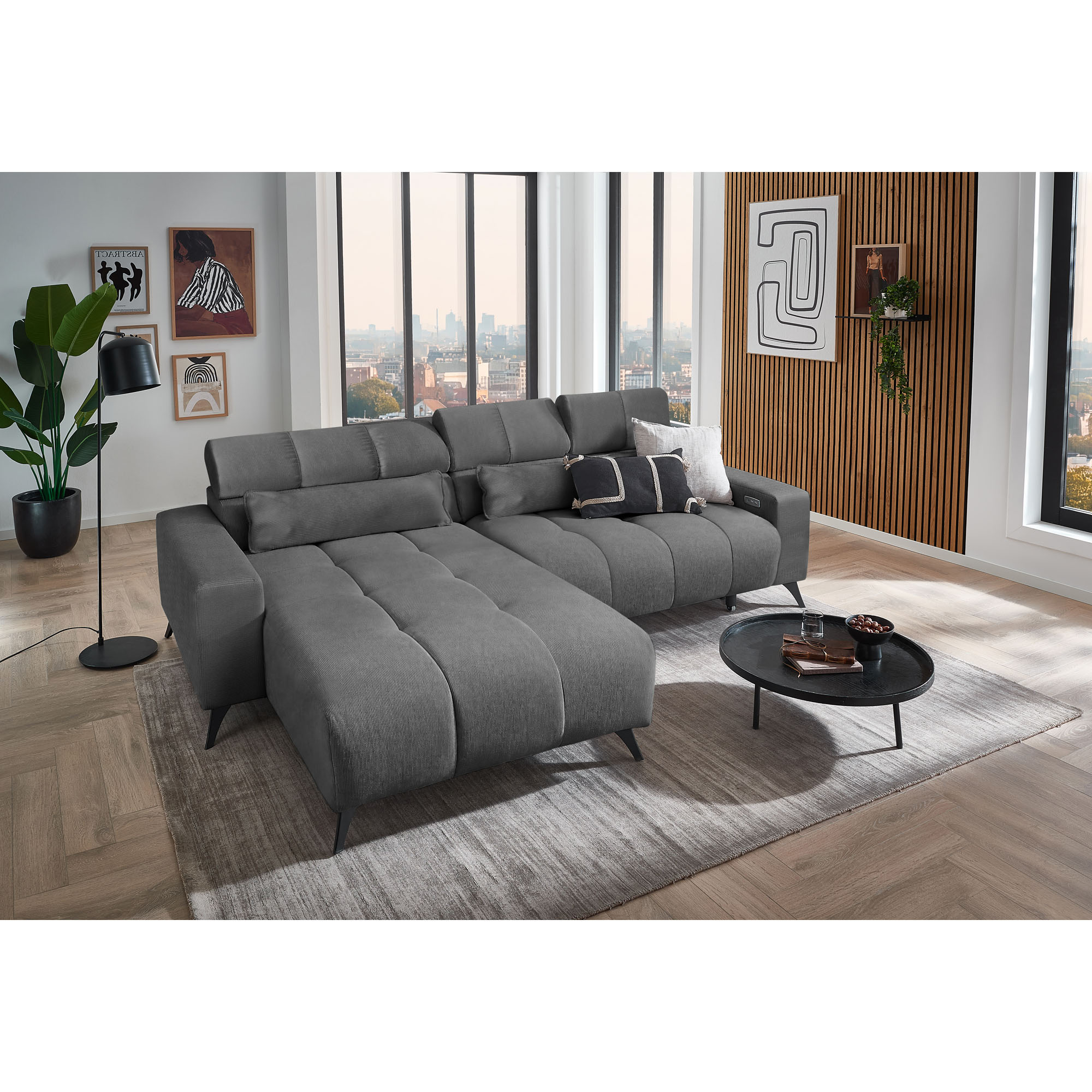 Dunkelgraues Ecksofa mit Ottomane links, verstellbaren Kopfstützen und Dekokissen in einem modern eingerichteten Wohnzimmer