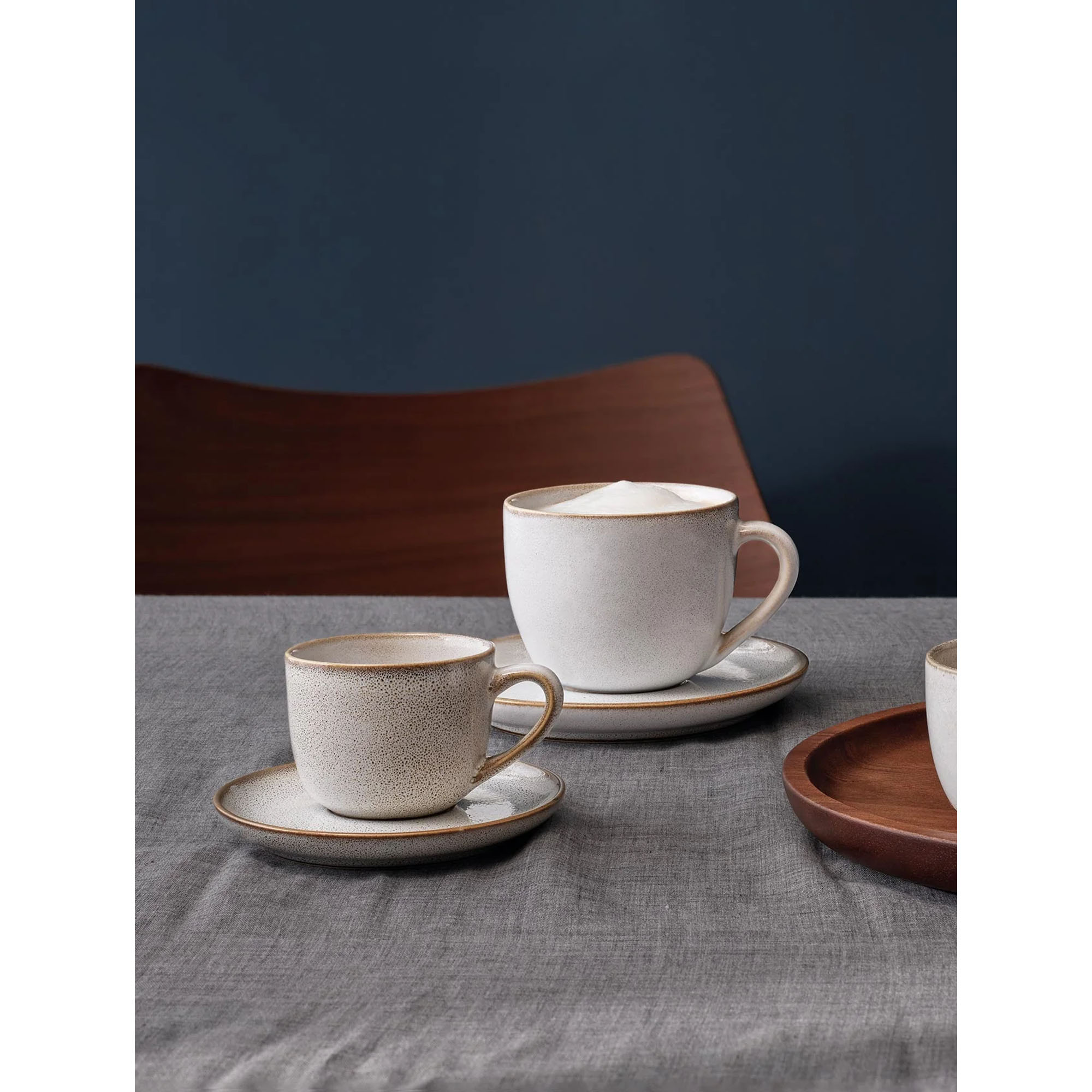 Cappuccinotasse mit Unterer der Serie Saisons, Farbe Nude in einer gedeckten Tischszene mit weiterem Geschirr.