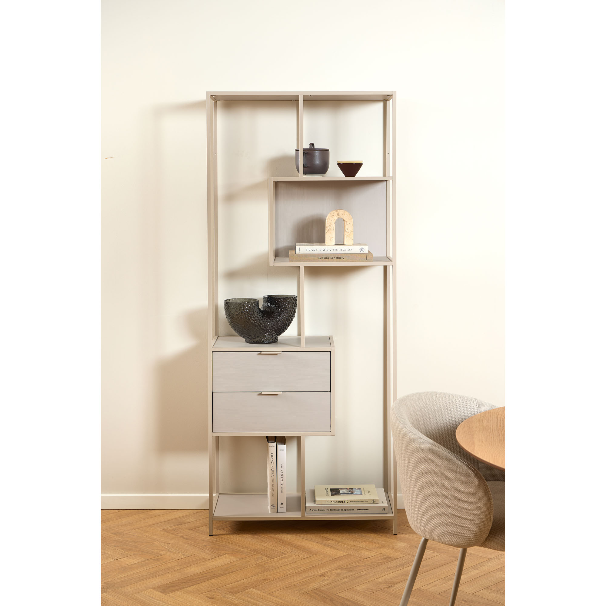 Das graue Regal steht in einem modernen Wohnraum und ist mit Büchern und Deko bestückt. Es fügt sich harmonisch in das Interieur ein