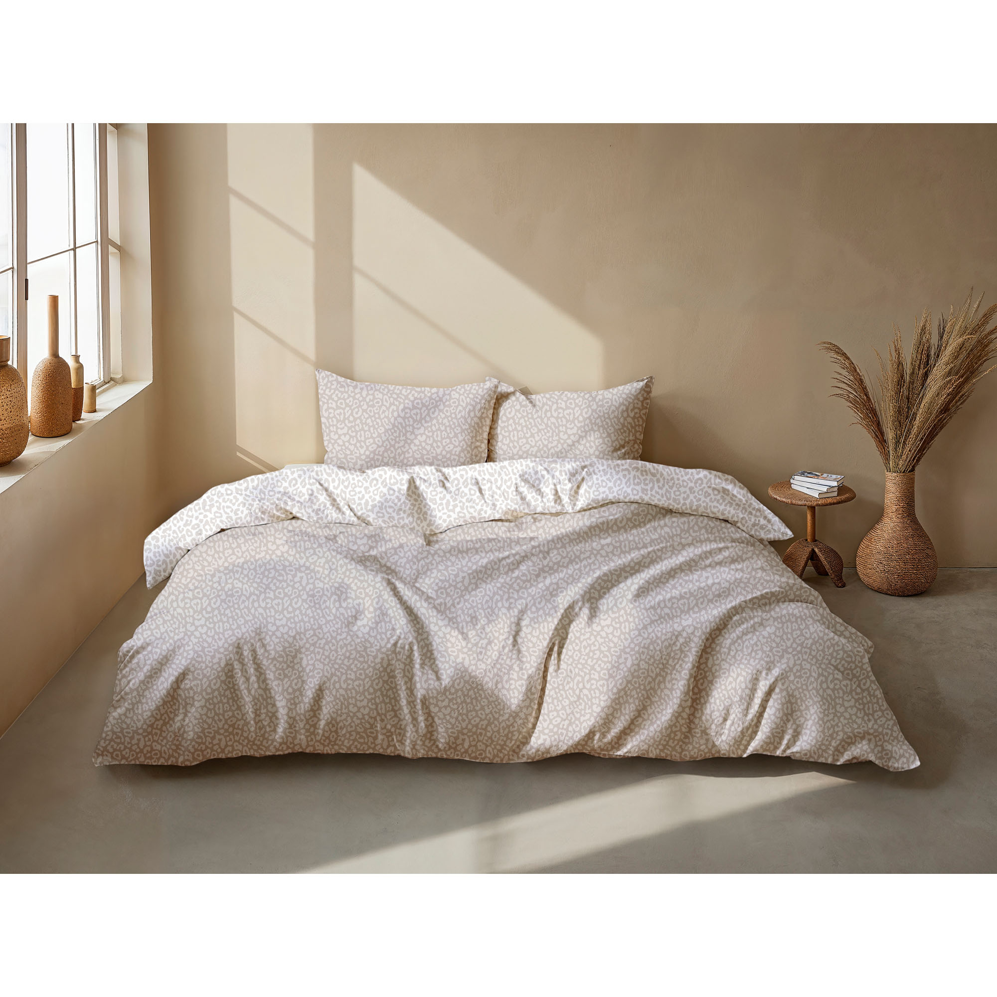 Bettwäsche Pantera in Natural, 135 x 200 cm: bezogenes Bett in seitlicher Schlafzimmerszene mit kleinem Leopardenmuster in Beige- und Grautönen.