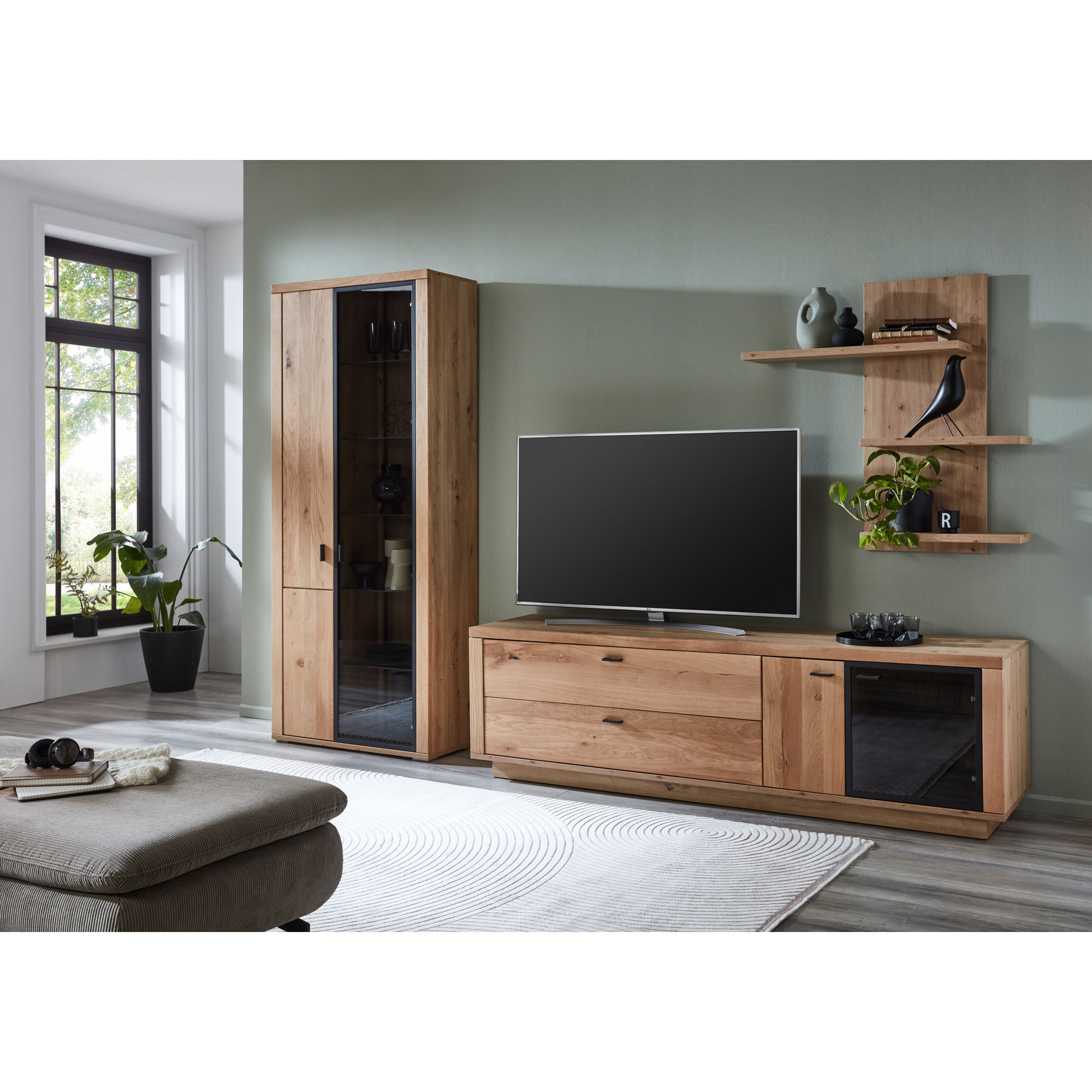 Moderne Wohnwand mit TV-Lowboard, hoher Vitrine und Wandregal in natürlicher Holzoptik in einem hell eingerichteten Wohnzimmer