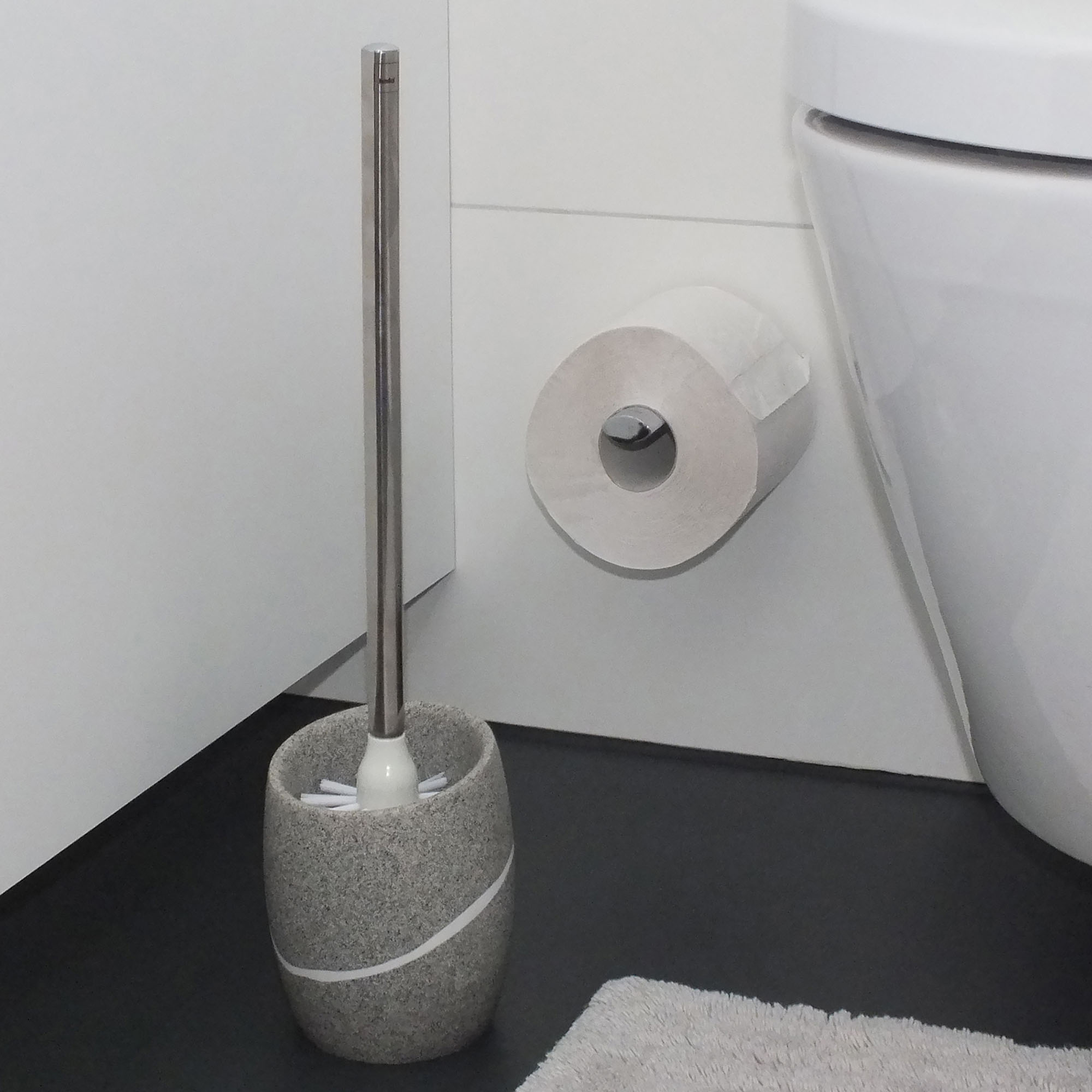 Freistehende WC Garnitur in Grau auf einem dunklen Boden neben einer weißen Toilette