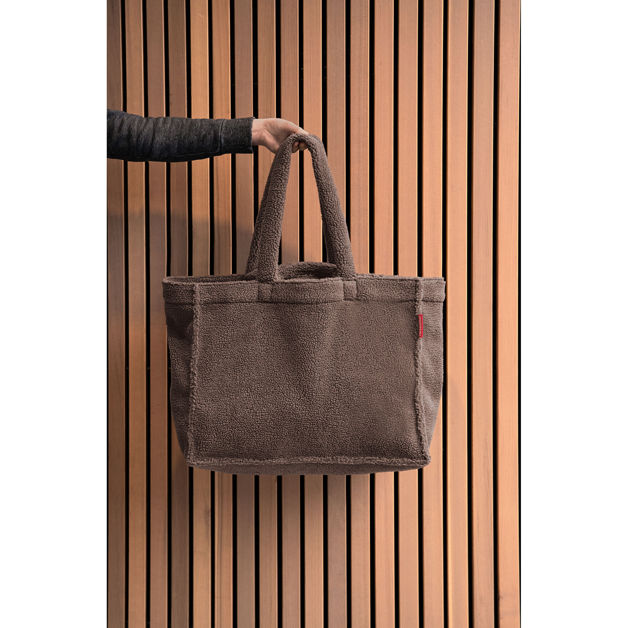 Shopper von Reisenthel, Modell Softshopper, in Schokoladenbraun aus Teddyfleece, von einer Person an den kurzen Griffen getragen