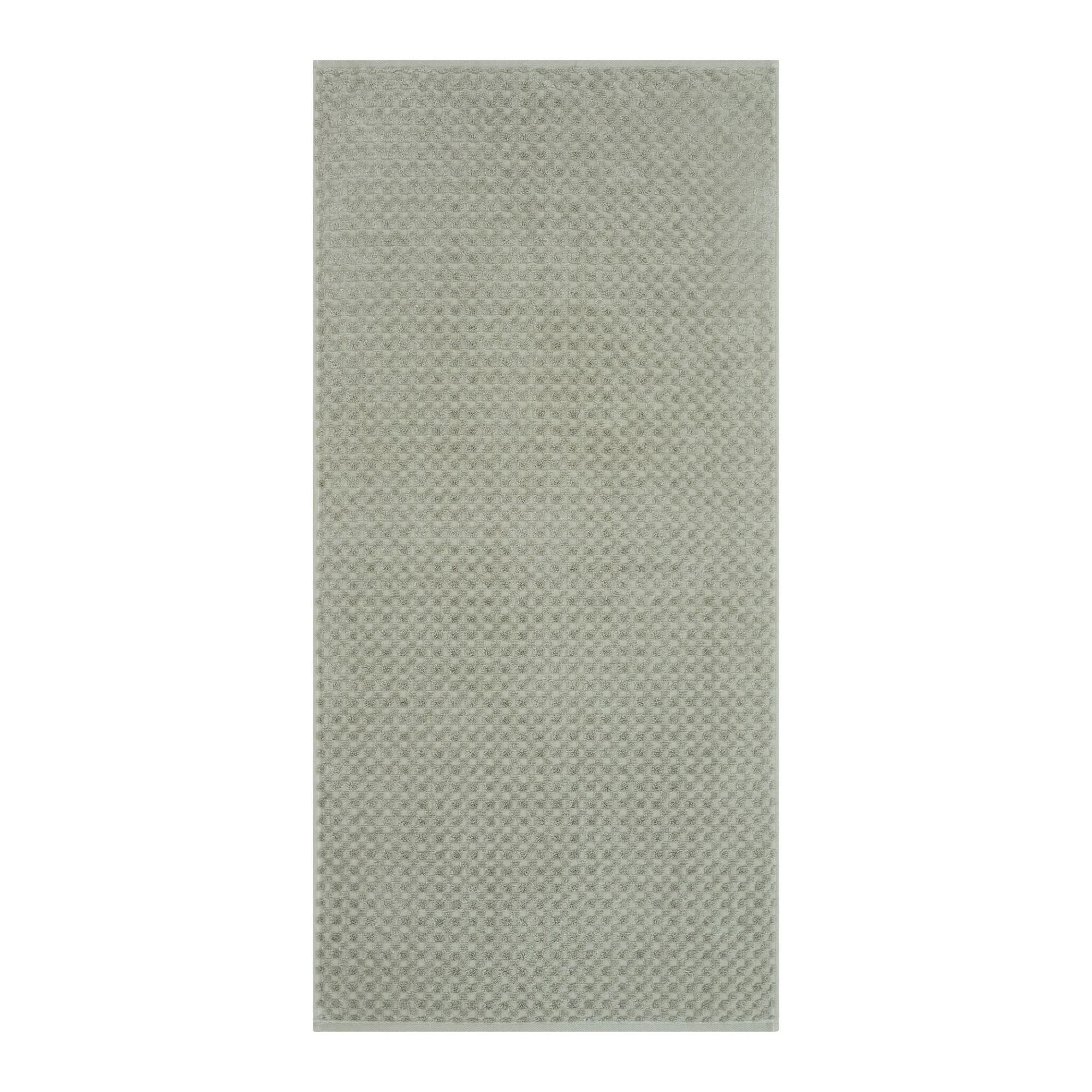 Handtuch in der Farbe Seegras, flach auf weißem Hintergrund gezeigt; die fein geometrisch strukturierte Oberfläche ist über die gesamte Fläche sichtbar.