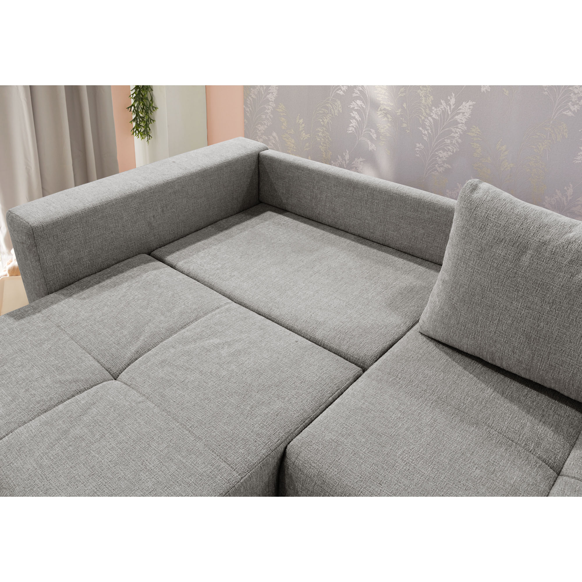 Detailaufnahme des grauen Schlafsofas mit gepolsterter Rückenlehne und großzügiger Liegefläche