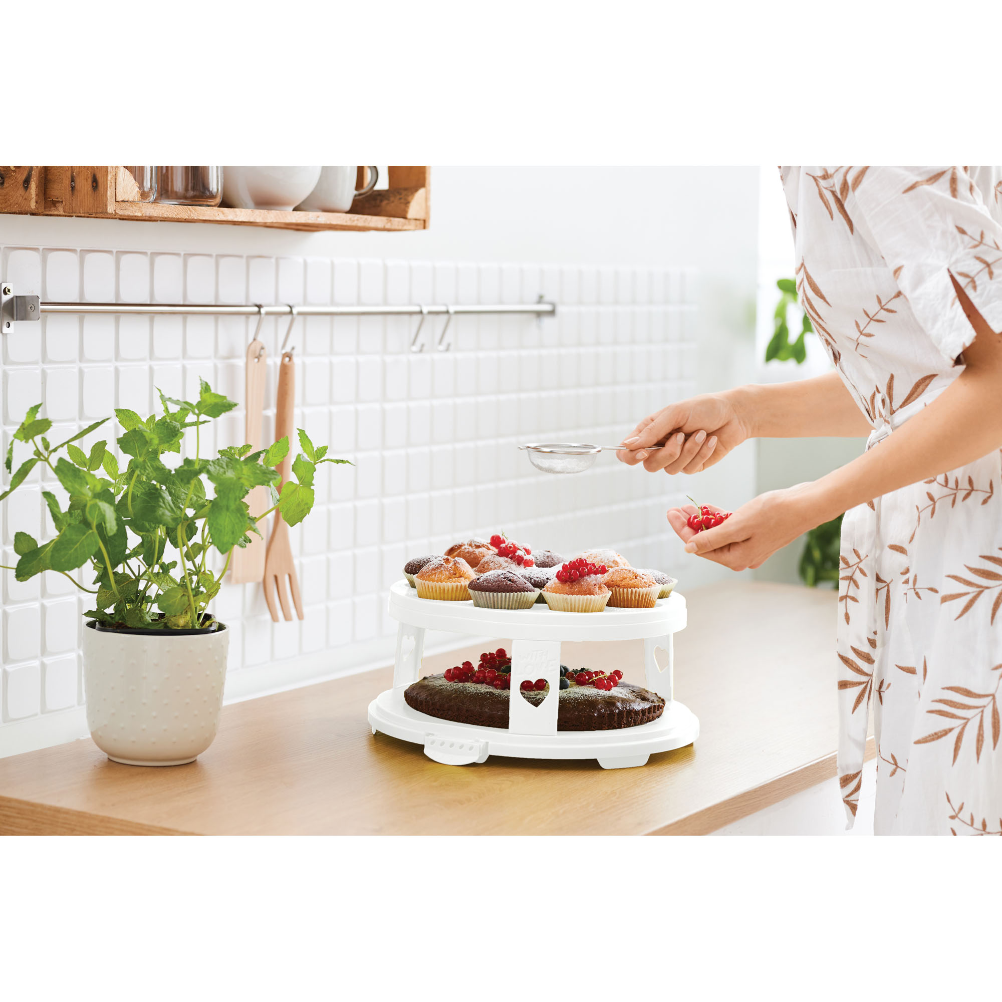 Runde Tortenhaube auf einem Tortenständer mit Kuchen auf einer Arbeitsfläche