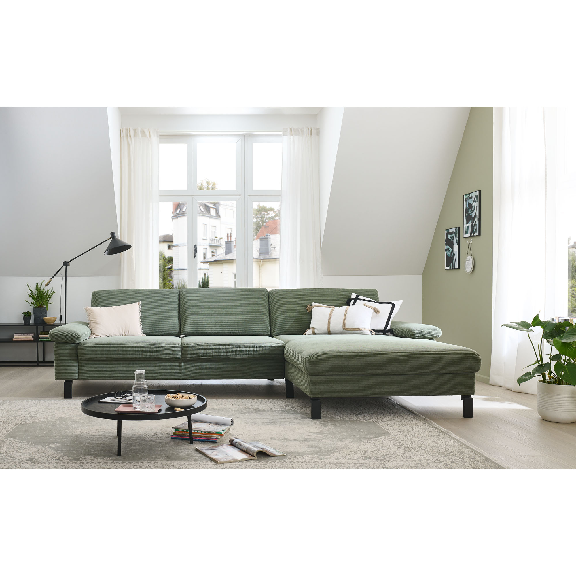 Ecksofa mit rechter Ottomane in einem hellen Wohnraum mit Teppich und Couchtisch