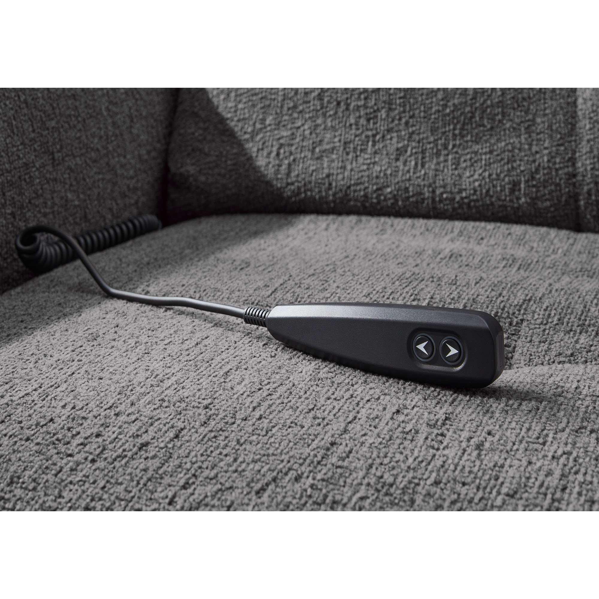 Schwarze Kabel-Fernbedienung zur Steuerung der elektrischen Relaxfunktion einer grauen Wohnlandschaft