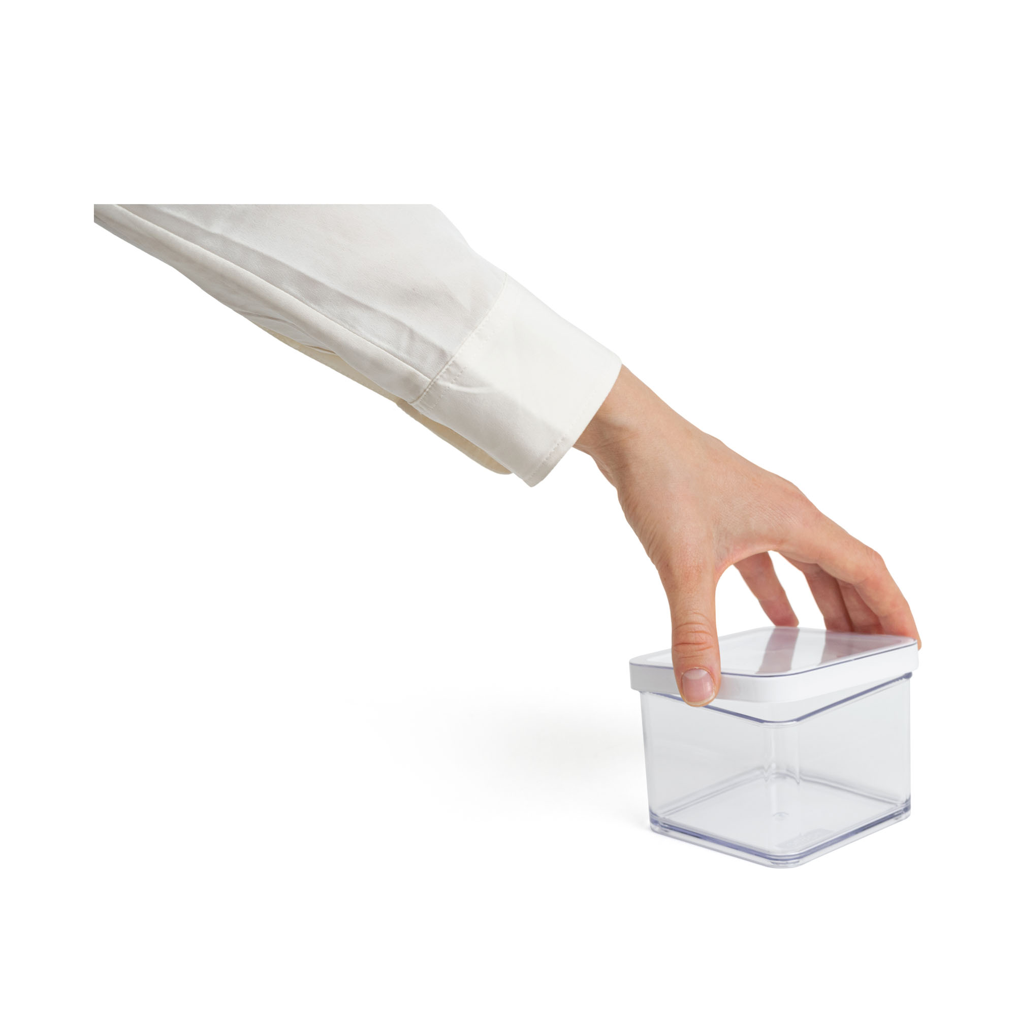 Hand greift eine transparente Aufbewahrungsbox mit Deckel vor weißem Hintergrund