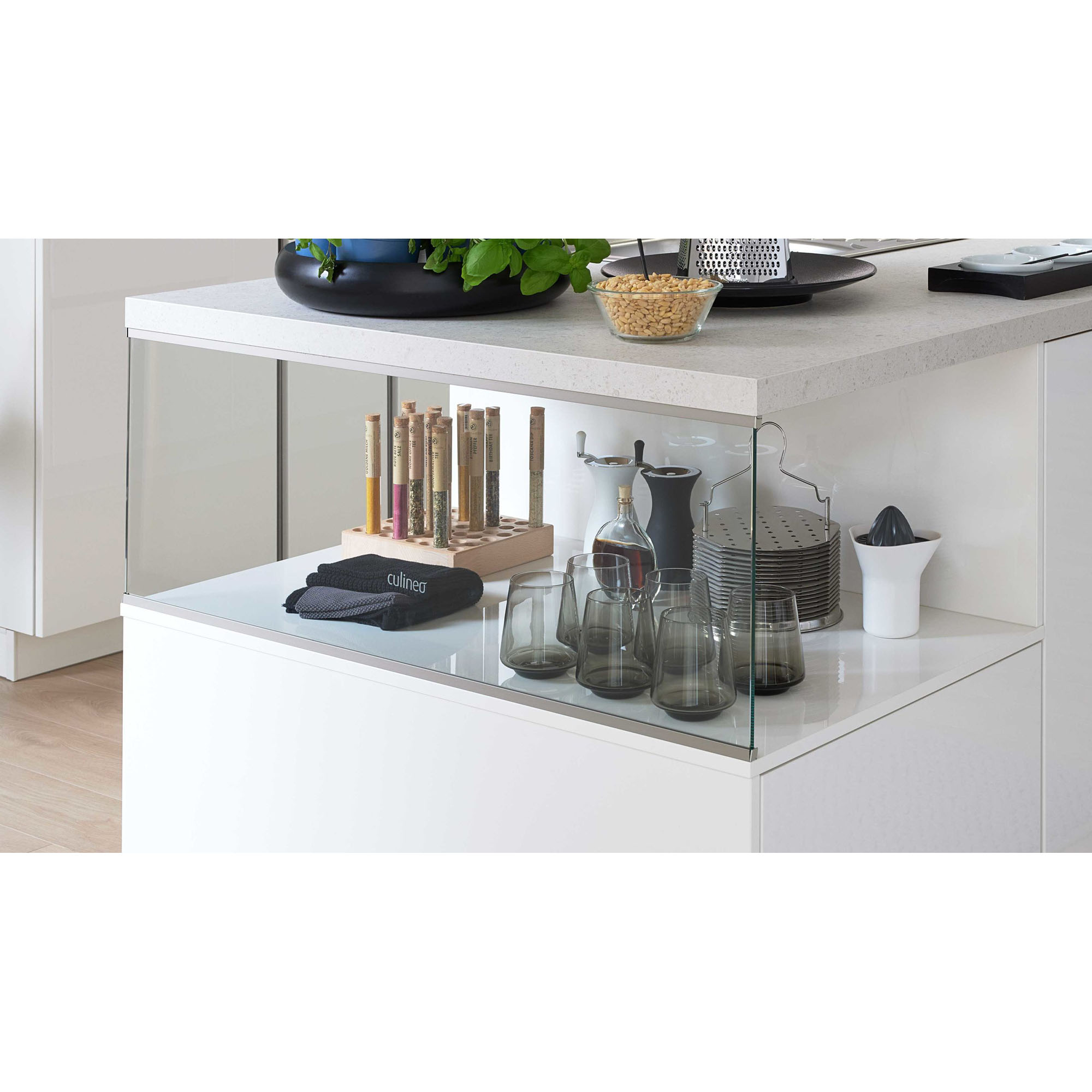 Detailansicht der Glasvitrine einer Kücheninsel mit Gläsern, Schalen und Gewürzbehältern auf weißer Fläche