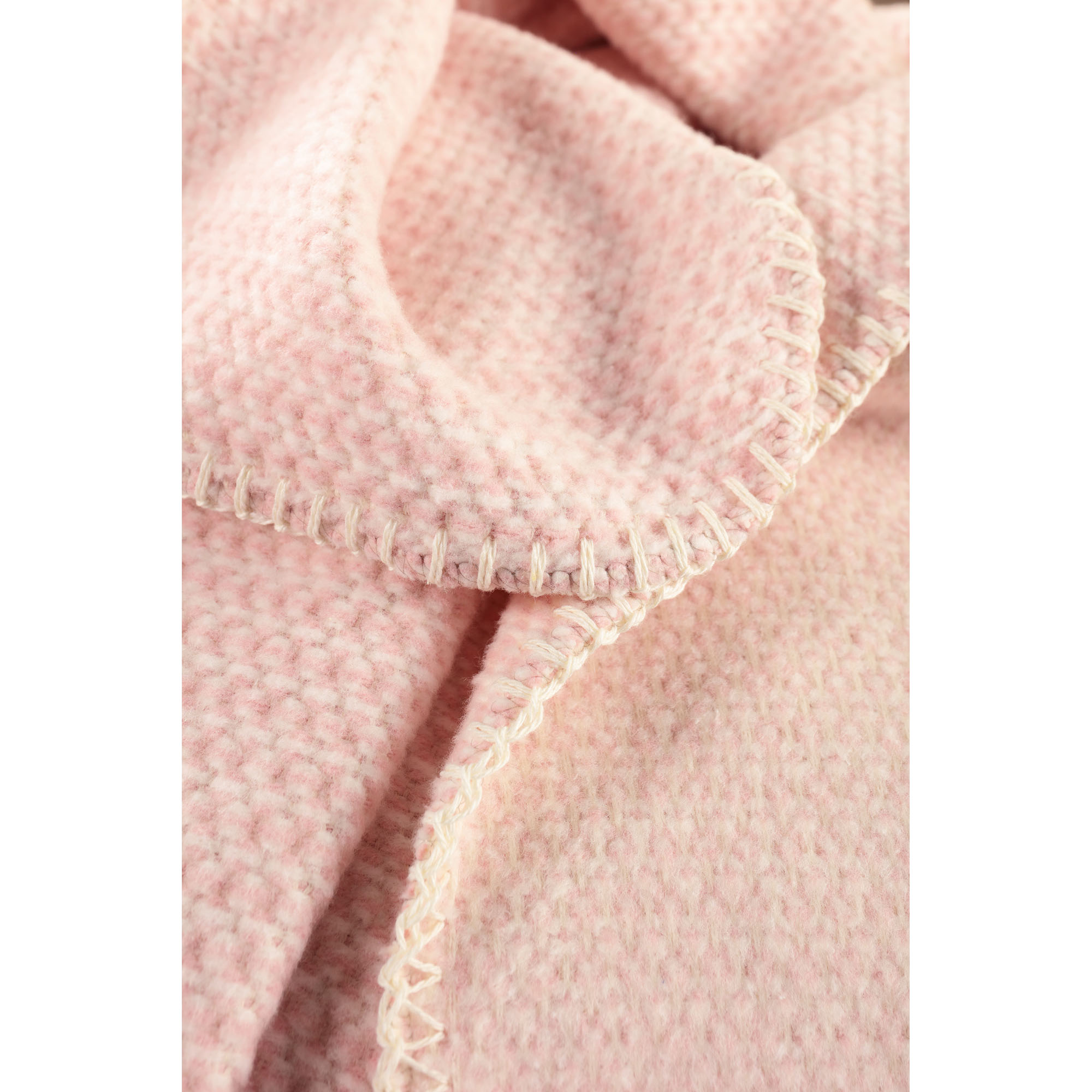 Nahaufnahme der Babydecke Cotton rose mit rosafarbener, fein strukturierter Oberfläche und weicher Stofffalte.