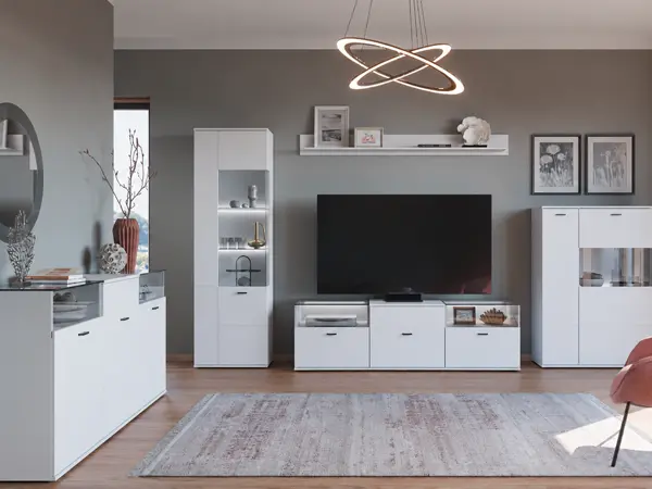 Komplett eingerichtetes Wohnzimmer mit moderner Wohnwand in Weiß bestehend aus TV-Lowboard, beleuchteter Vitrine, Sideboard, Wandregal und Couchtisch vor grauer Wand1