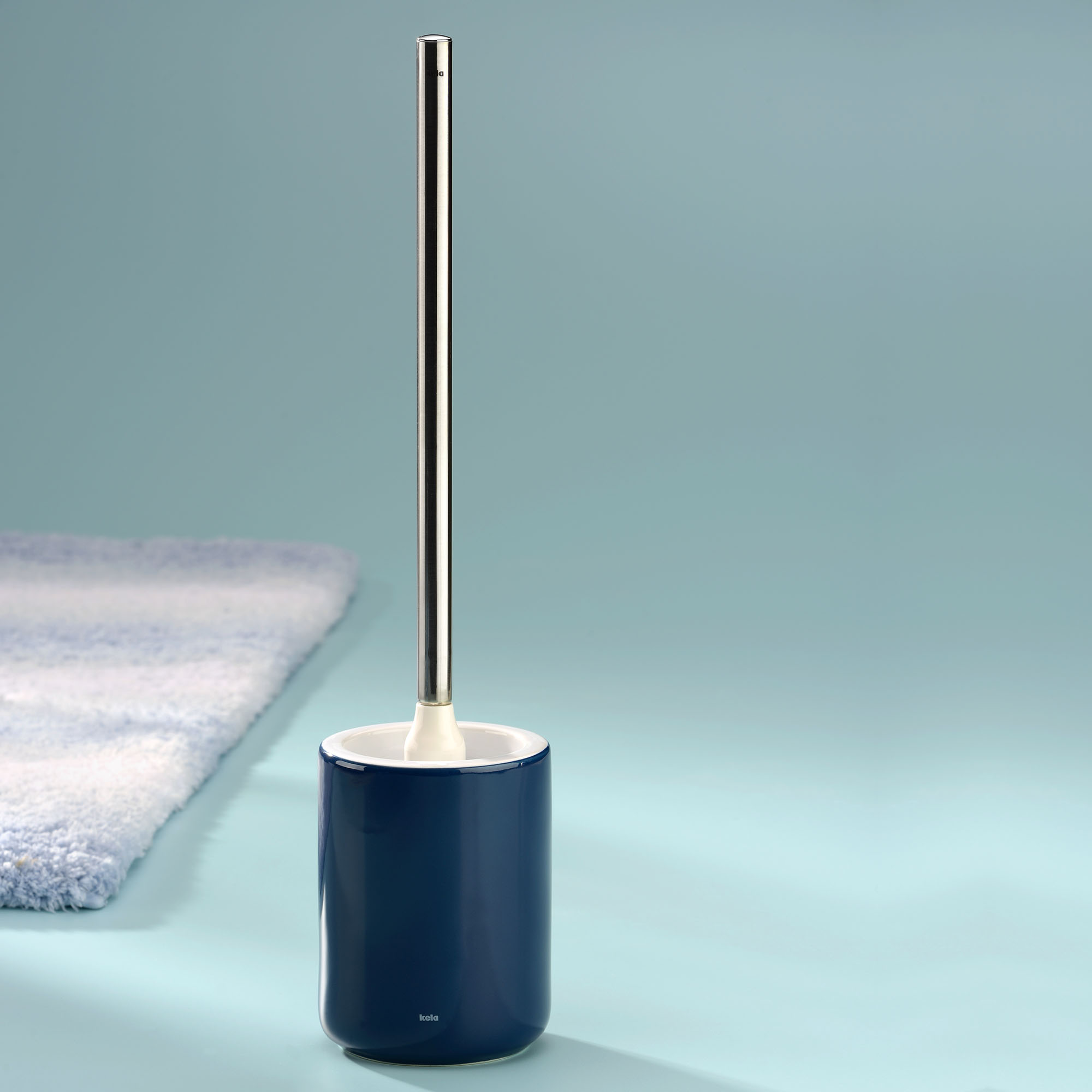 WC Garnitur in Indigoblau auf einer hellblauen Fläche neben zusammengelegten Handtüchern