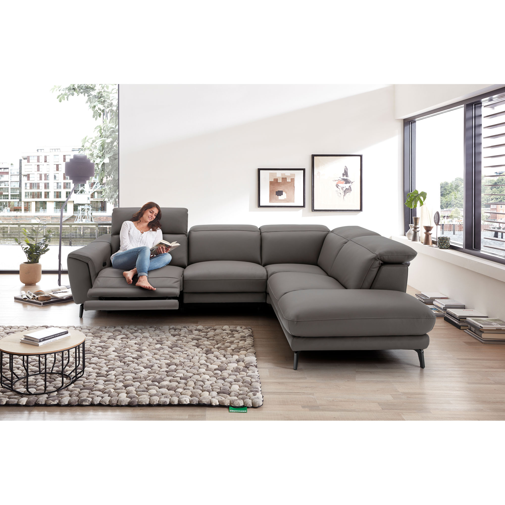 Graues Ecksofa mit Recamiere in einem eingerichteten Wohnraum mit Teppich und Couchtisch