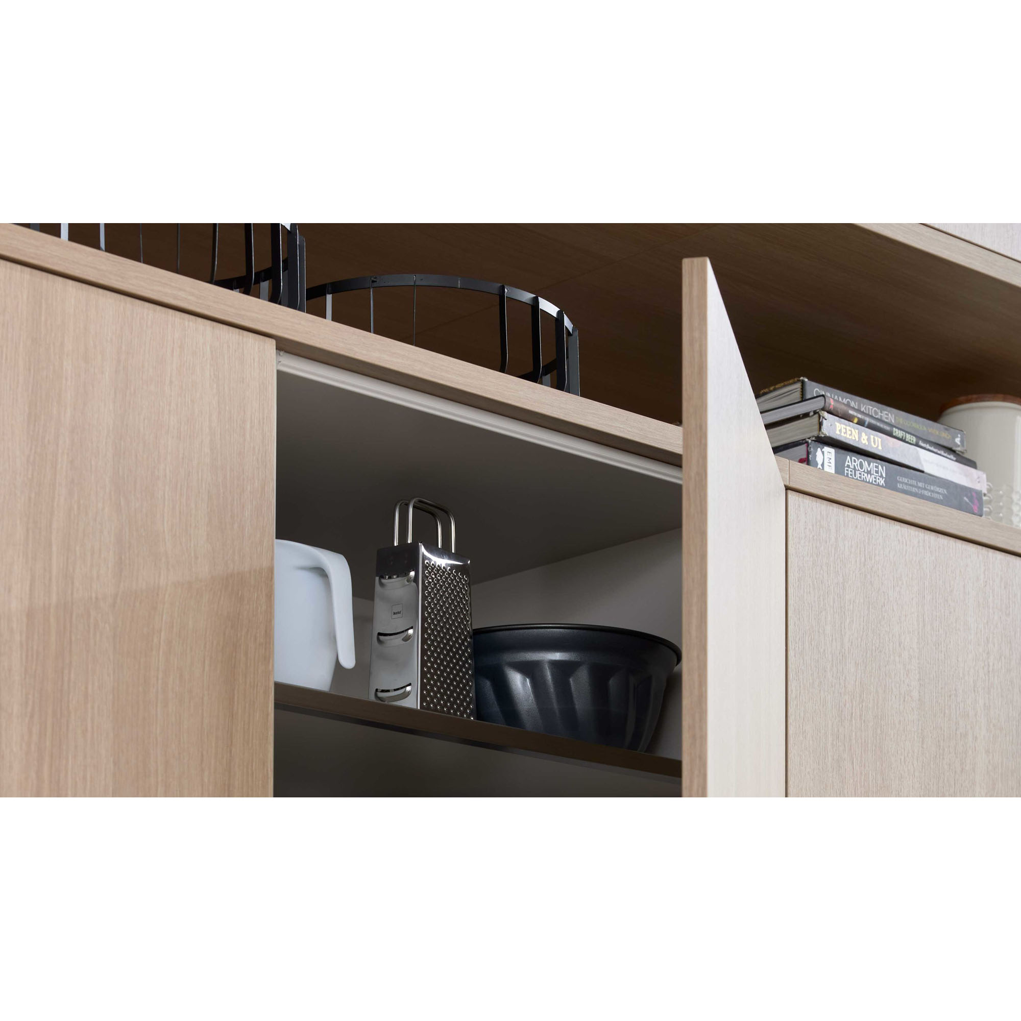 Geöffneter Küchenschrank mit Haushaltsutensilien wie Reibe, Krug und Schüssel.
