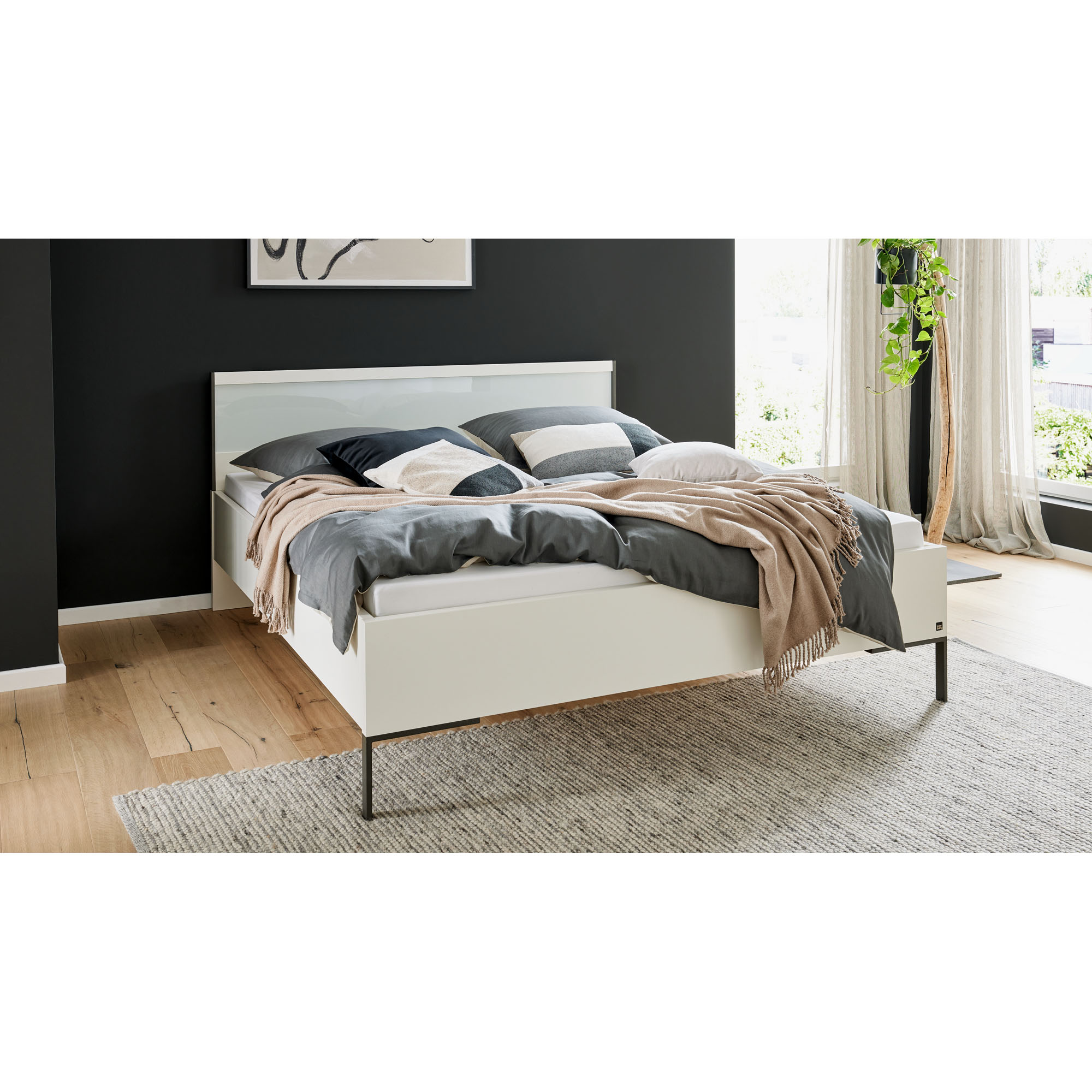 Weißes Bett mit Kopfteil in einem Schlafzimmer mit Bettwäsche und Tagesdecke
