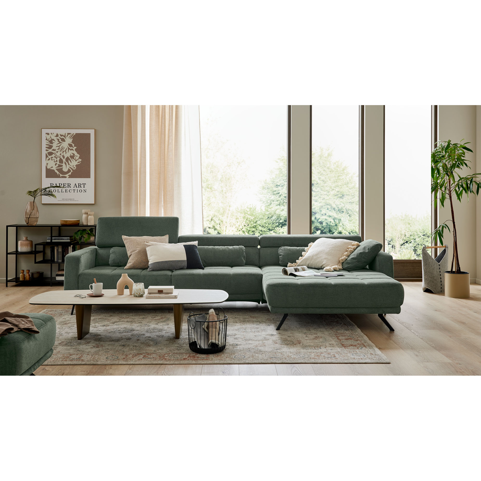 grünes Ecksofa Interliving 4303 mit linker Recamiere in einem hellen Wohnzimmer mit Couchtisch, Teppich und großen Fenstern