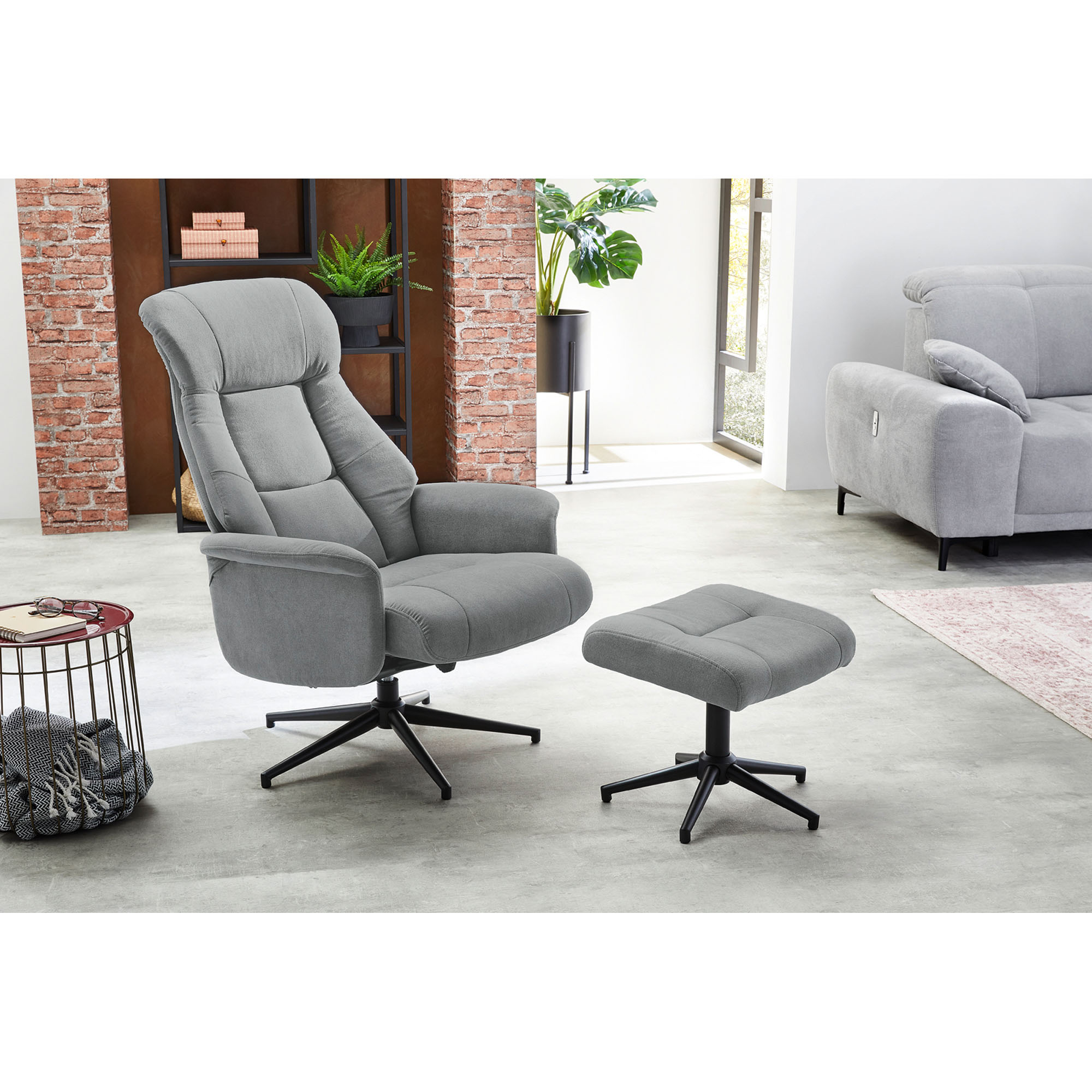 Stilvolles Wohnzimmer mit Relaxsessel und Hocker in Grau, dekoriert mit modernen Möbeln und Pflanzen.