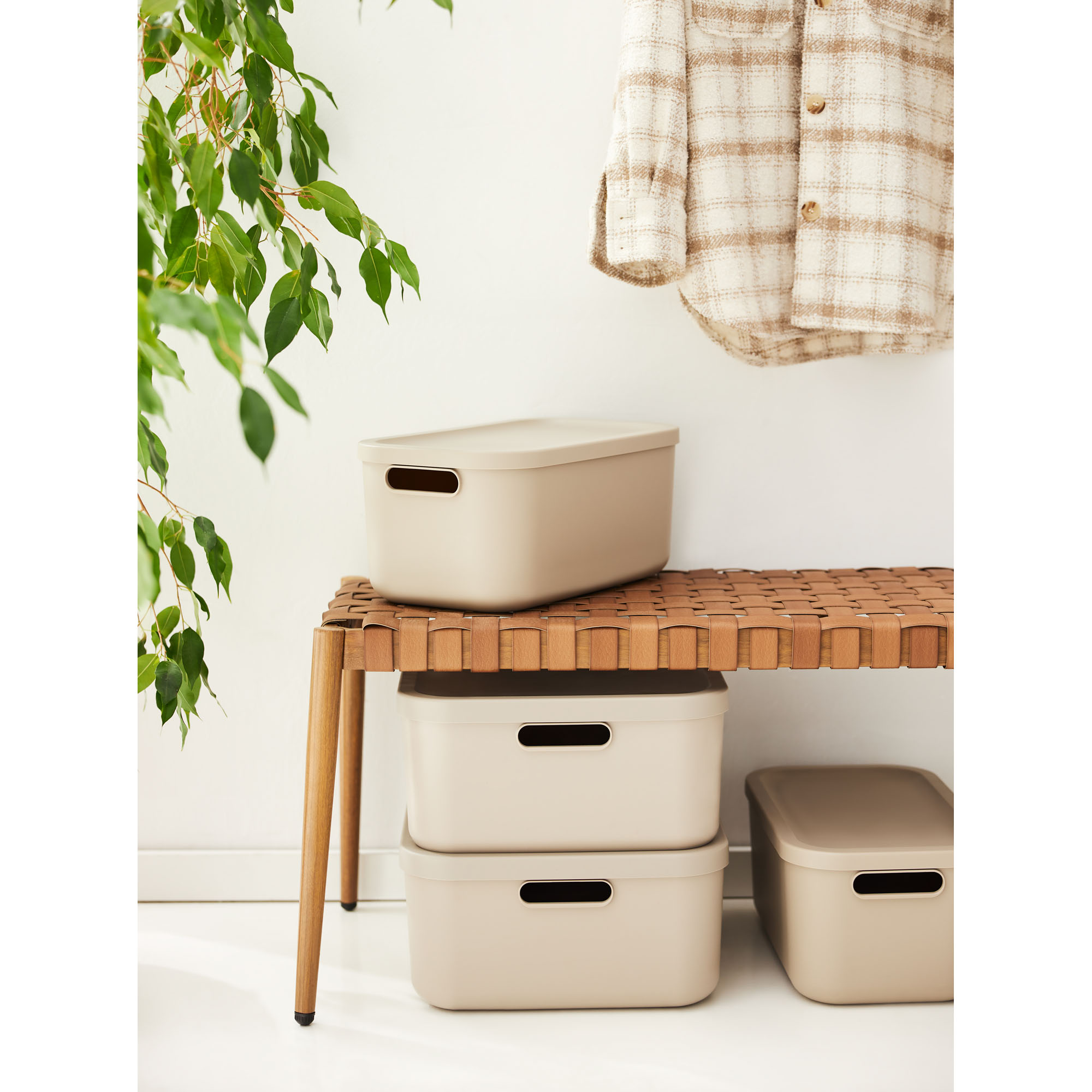 Mehrere beige Aufbewahrungsboxen mit Deckeln unter einem Tisch im Wohnraum