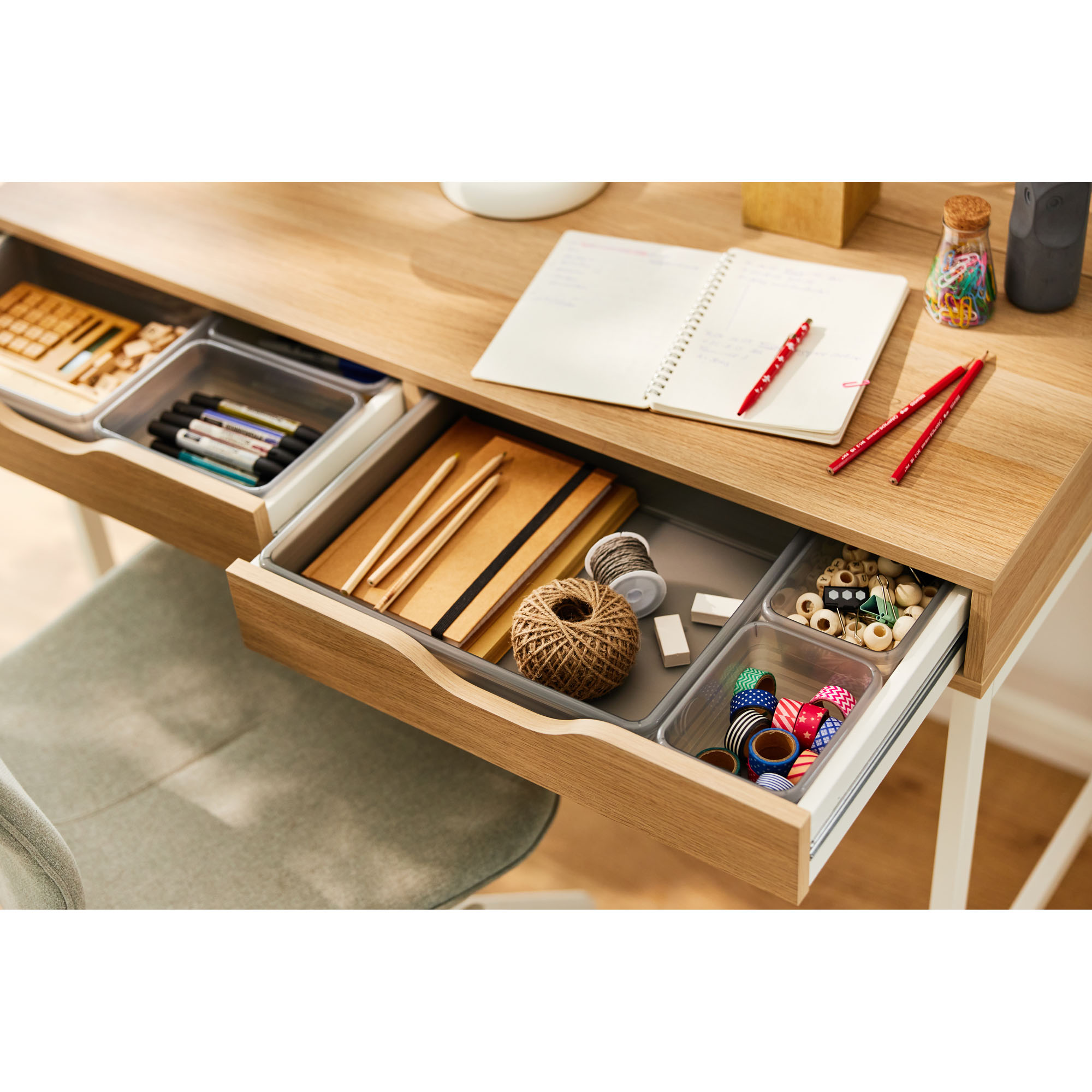 Graue Schubladenbox mit Büroartikeln in einer geöffneten Schreibtischschublade
