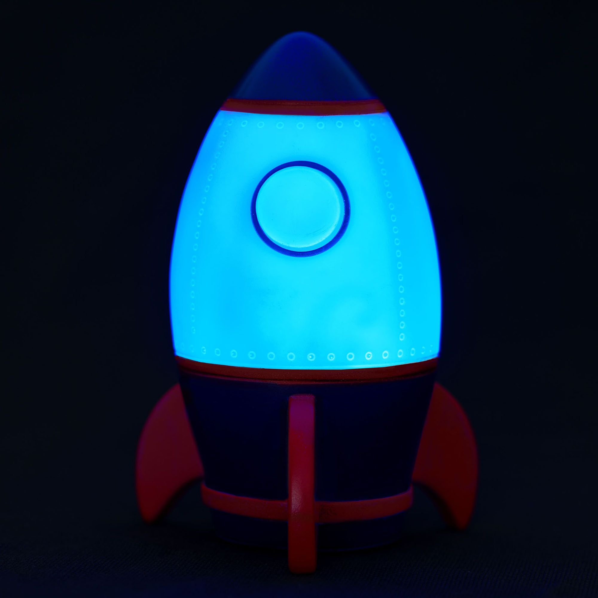 Nachtlicht in Raketenform, vor schwarzem Hintergrund blau leuchtend gezeigt.