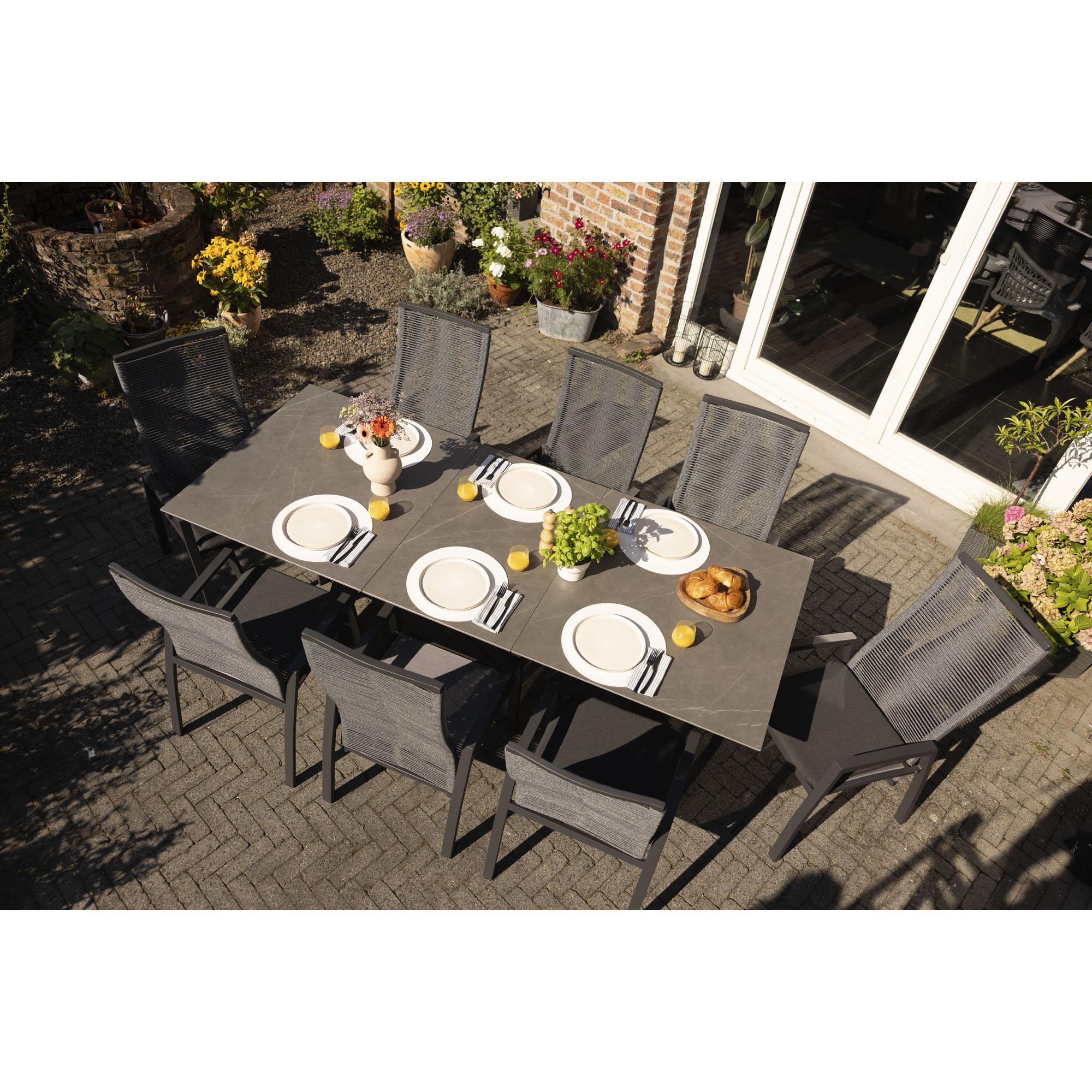 Gartentisch mit mehreren Gartenstühlen auf einer Terrasse von oben fotografiert