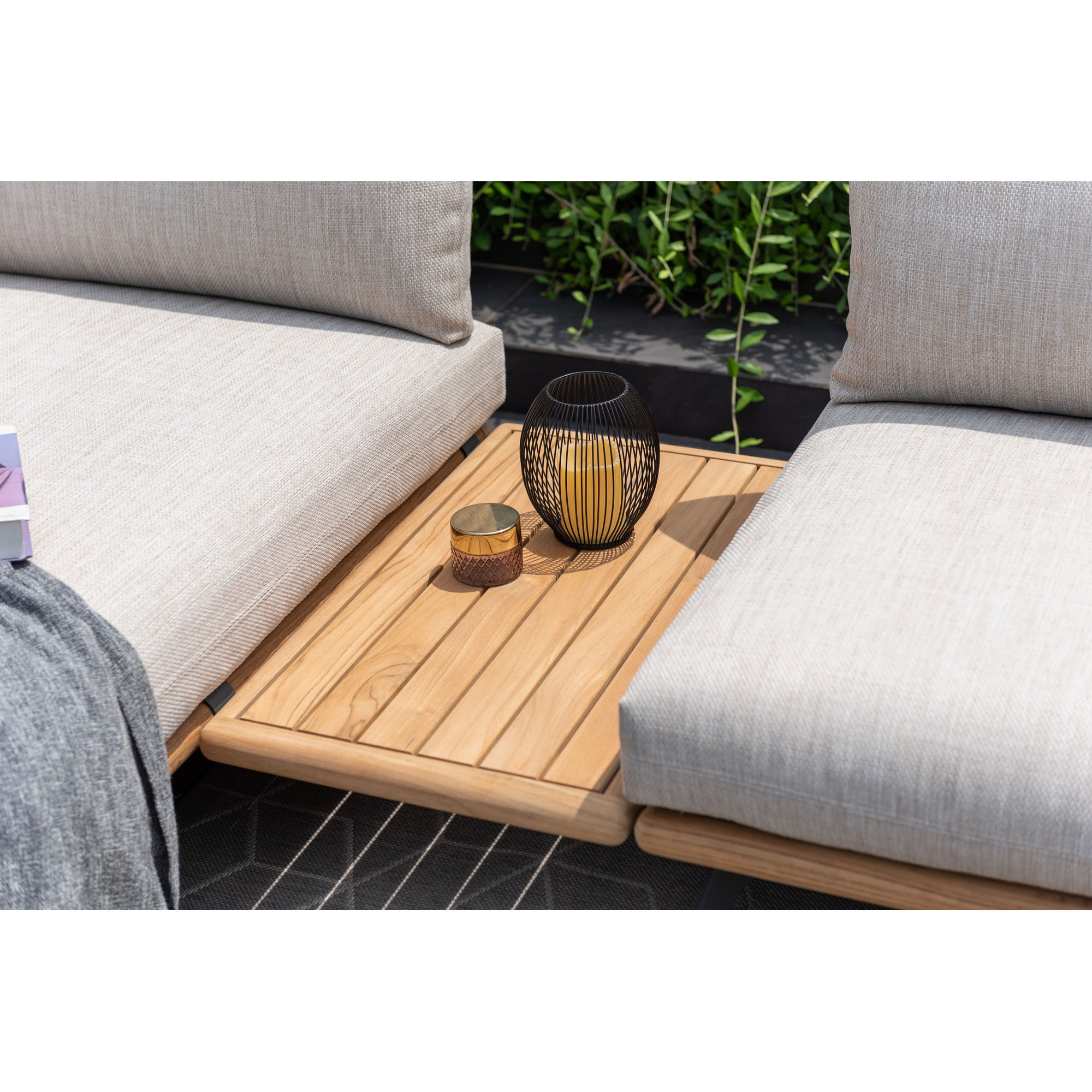 Ablageelement aus Holz zwischen zwei gepolsterten Garten Sofa Elementen mit Dekoration auf einer Terrasse