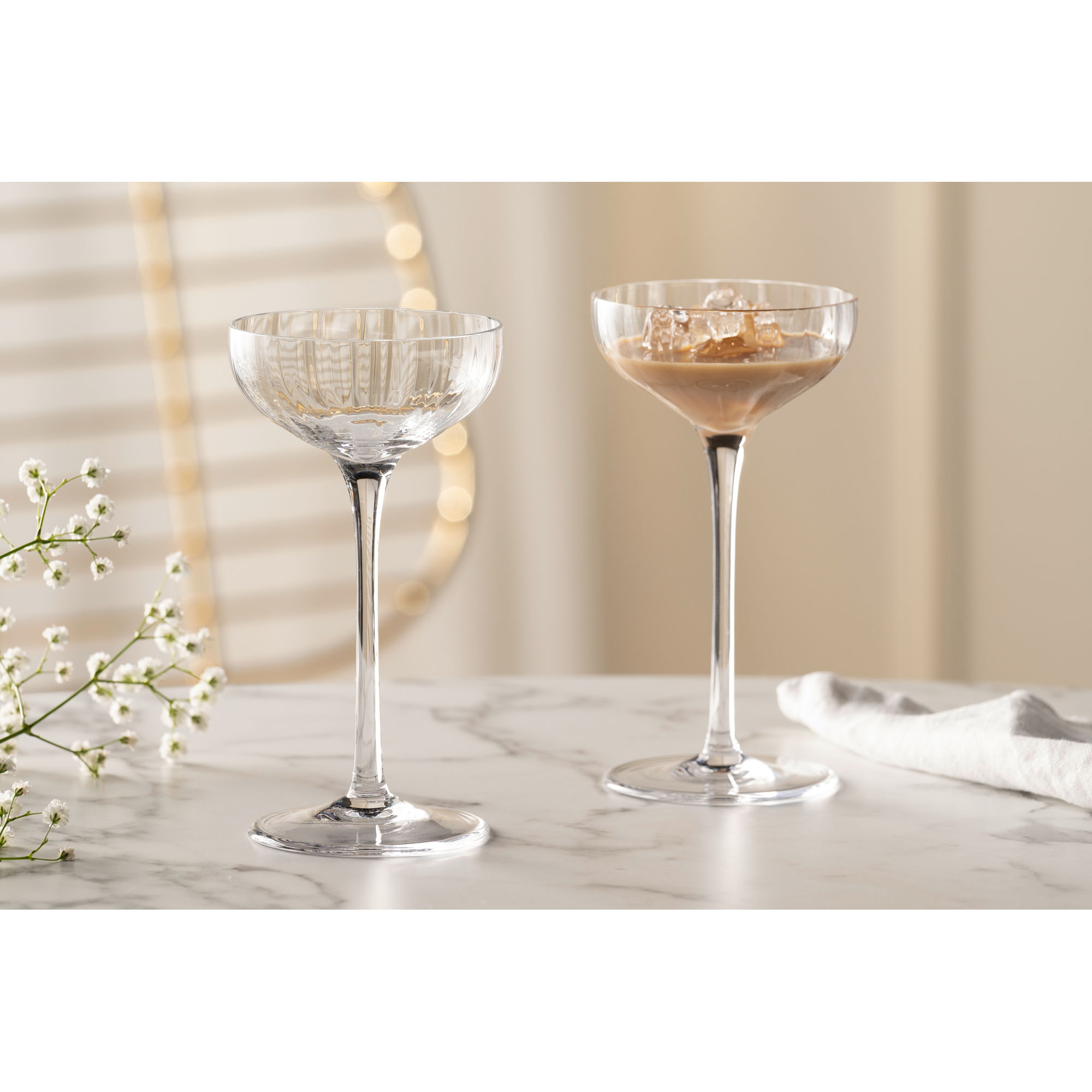 Zwei Cocktailschalen eine gefüllt mit cremigem Getränk auf hellem Tisch dekoriert