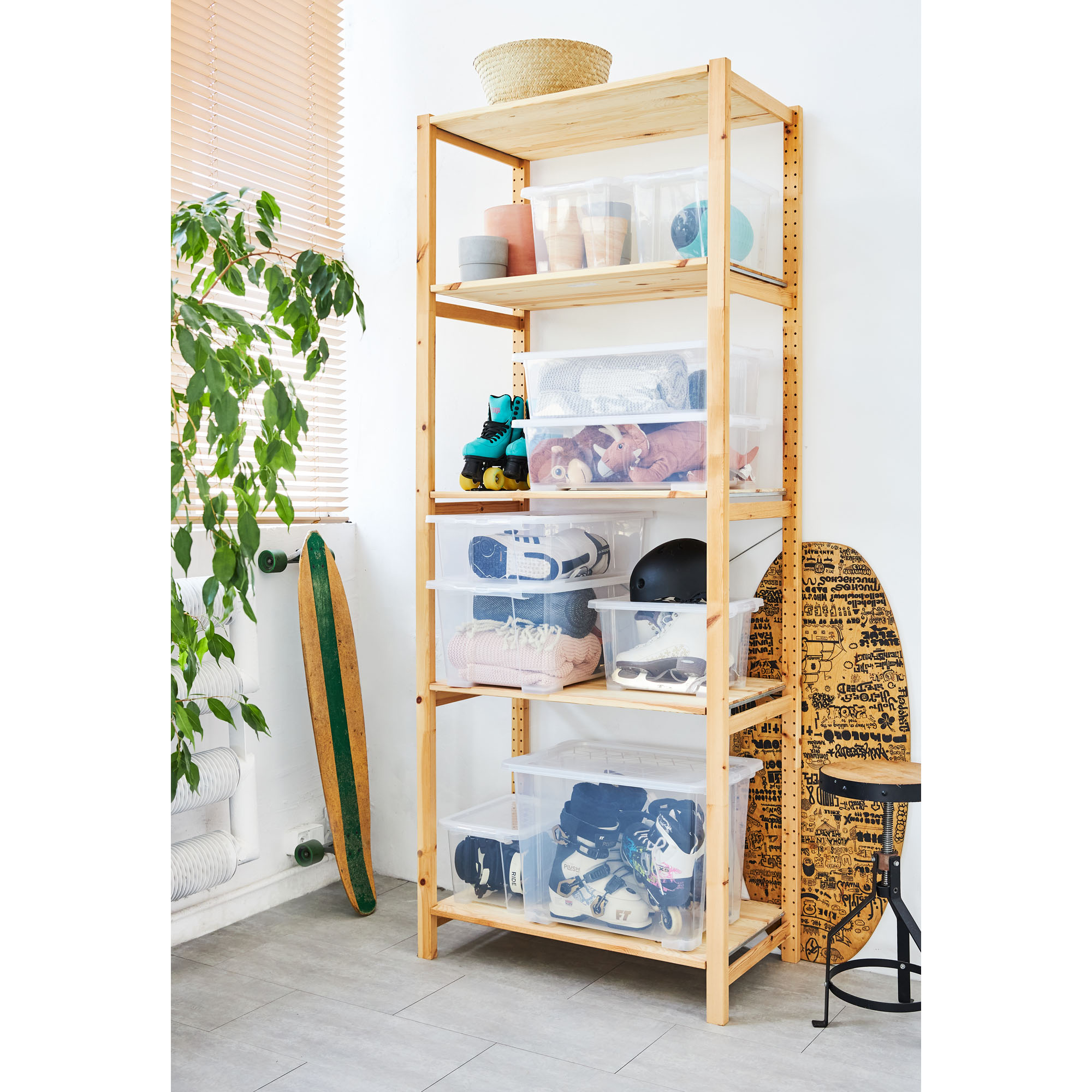 Transparente Aufbewahrungsbox in einem Holzregal mit verschiedenen Haushaltsgegenständen
