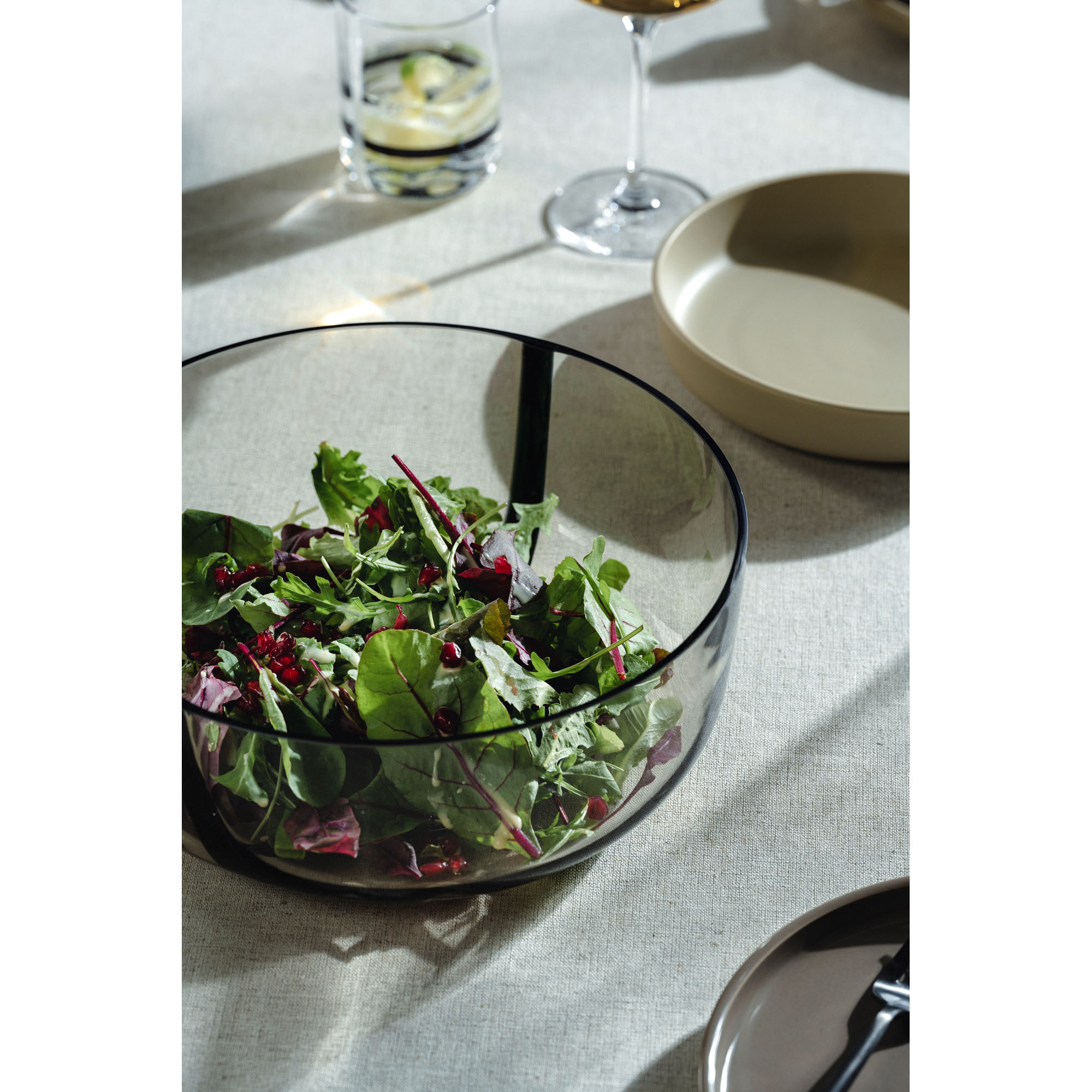 Glasschale gefüllt mit frischem Blattsalat auf gedecktem Tisch