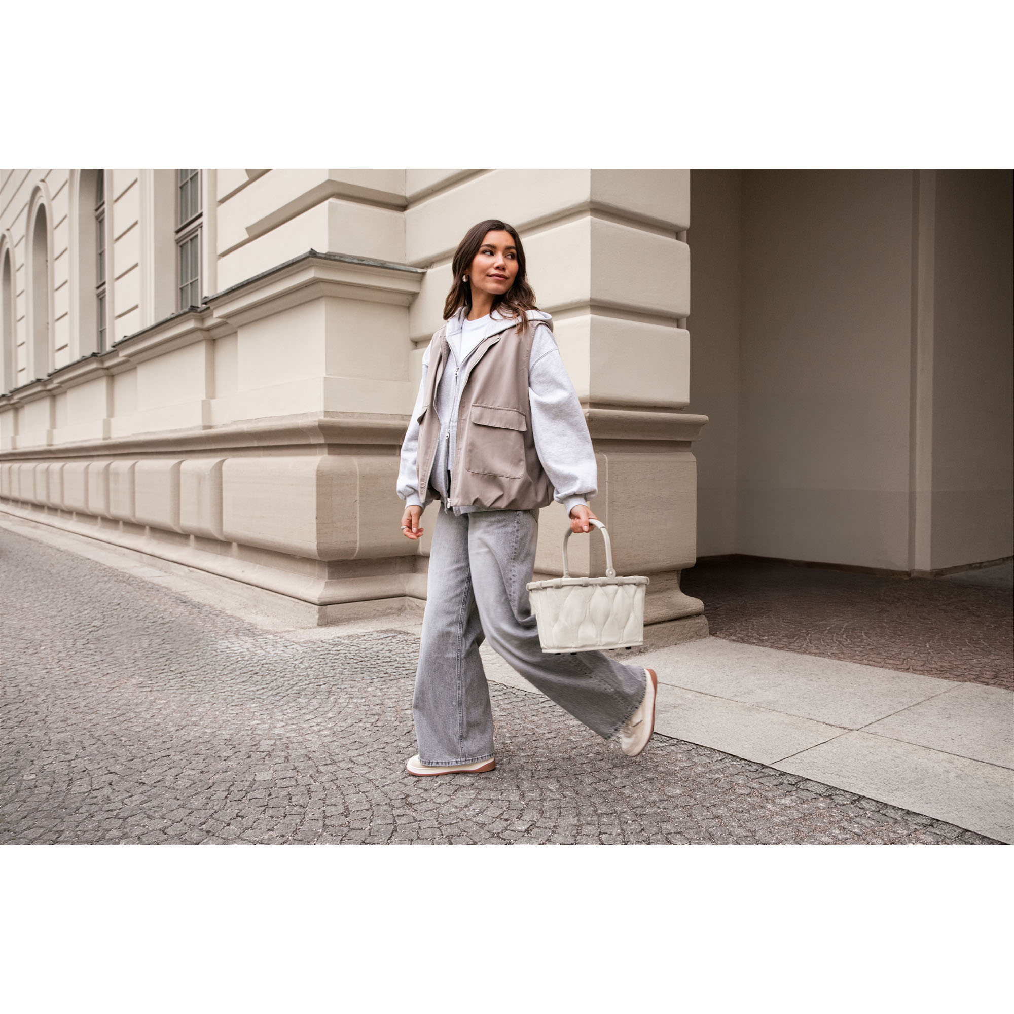 Kleiner Einkaufskorb von Reisenthel, Modell Carrybag XS, in hellem Steinbeige mit Steppstruktur, von einer Person am Tragegriff getragen
