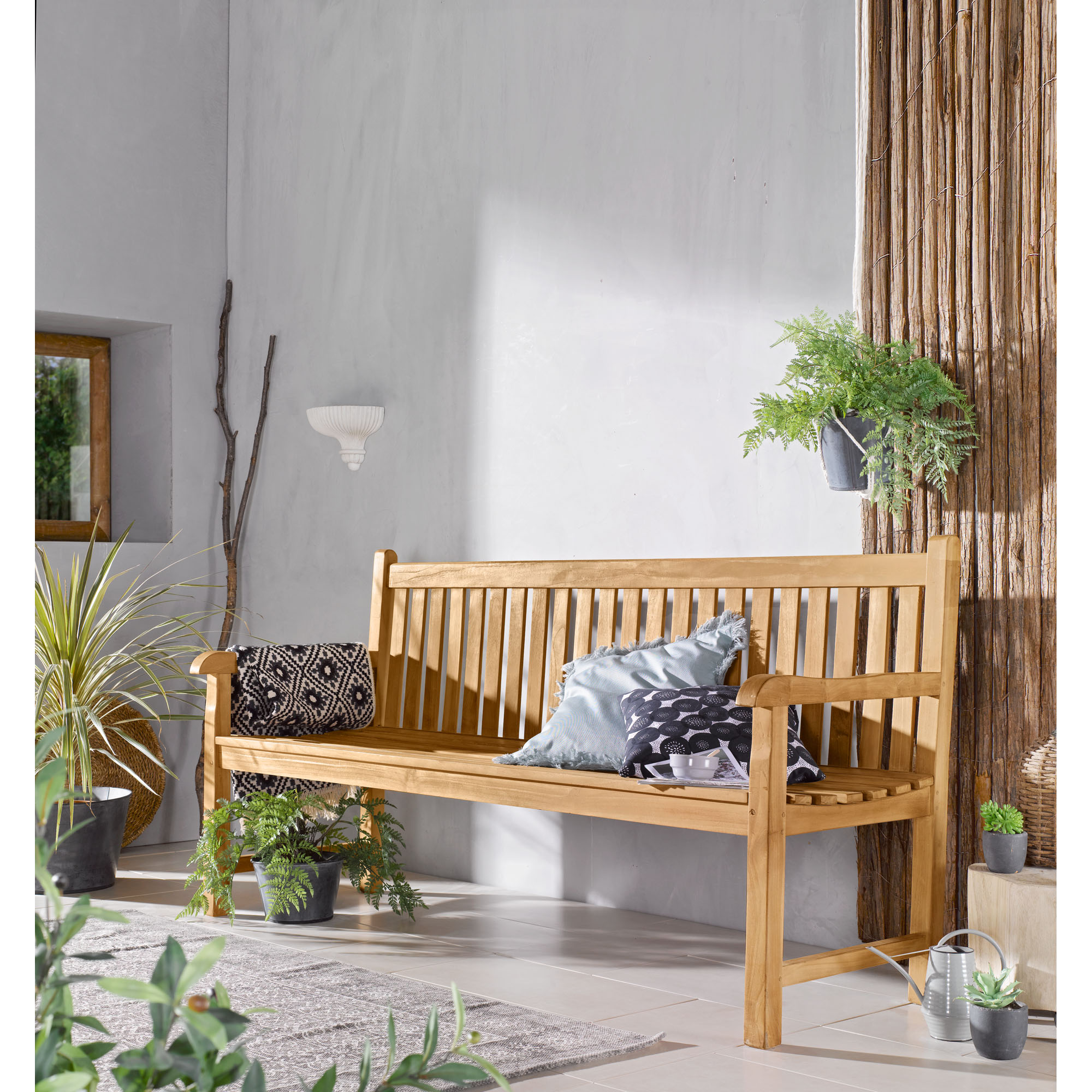 Sitzbank aus Holz mit Rückenlehne und Armlehnen in einem Wohnraum mit Pflanzen und Kissen