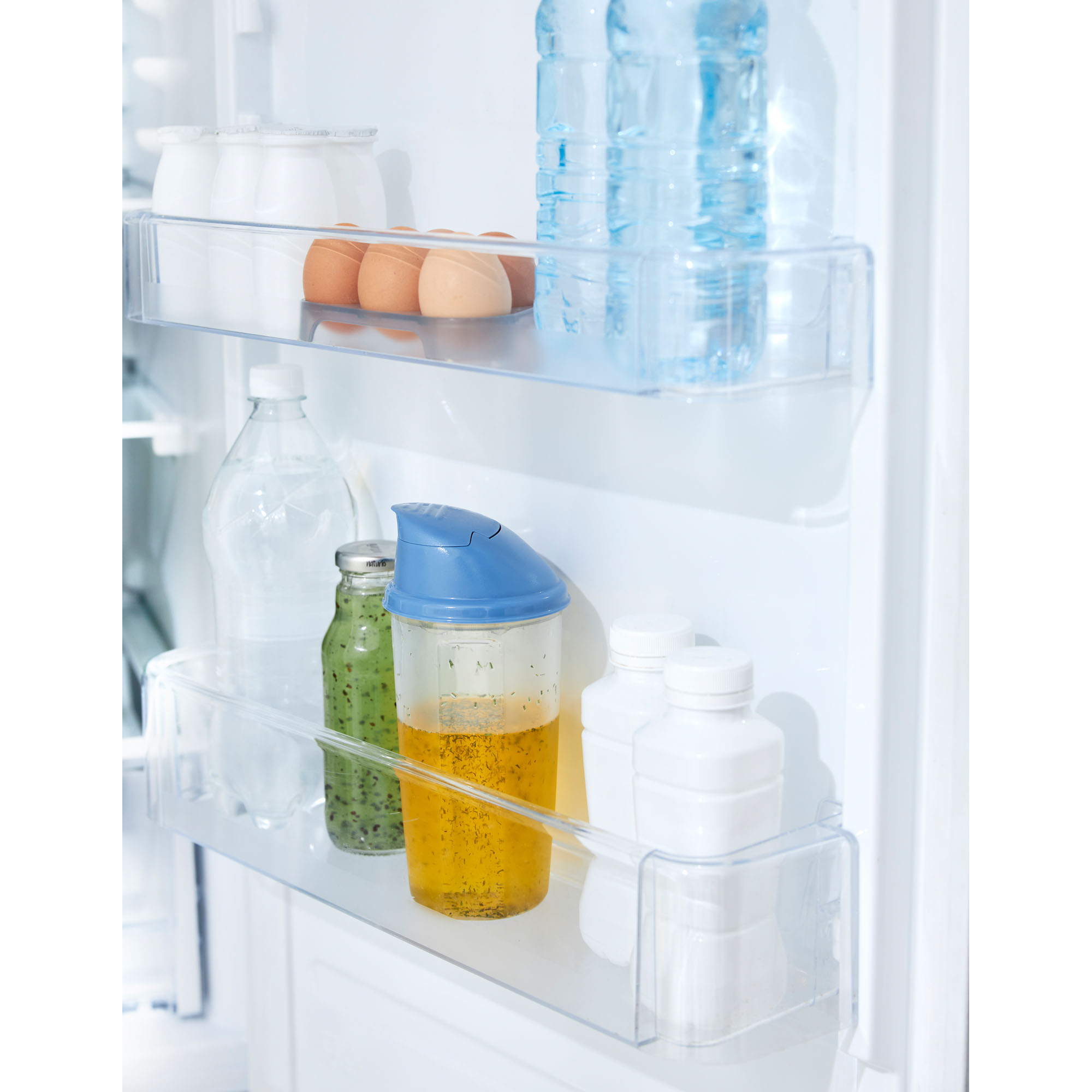 Transparenter Shaker mit blauem Deckel in einem Kühlschrankfach