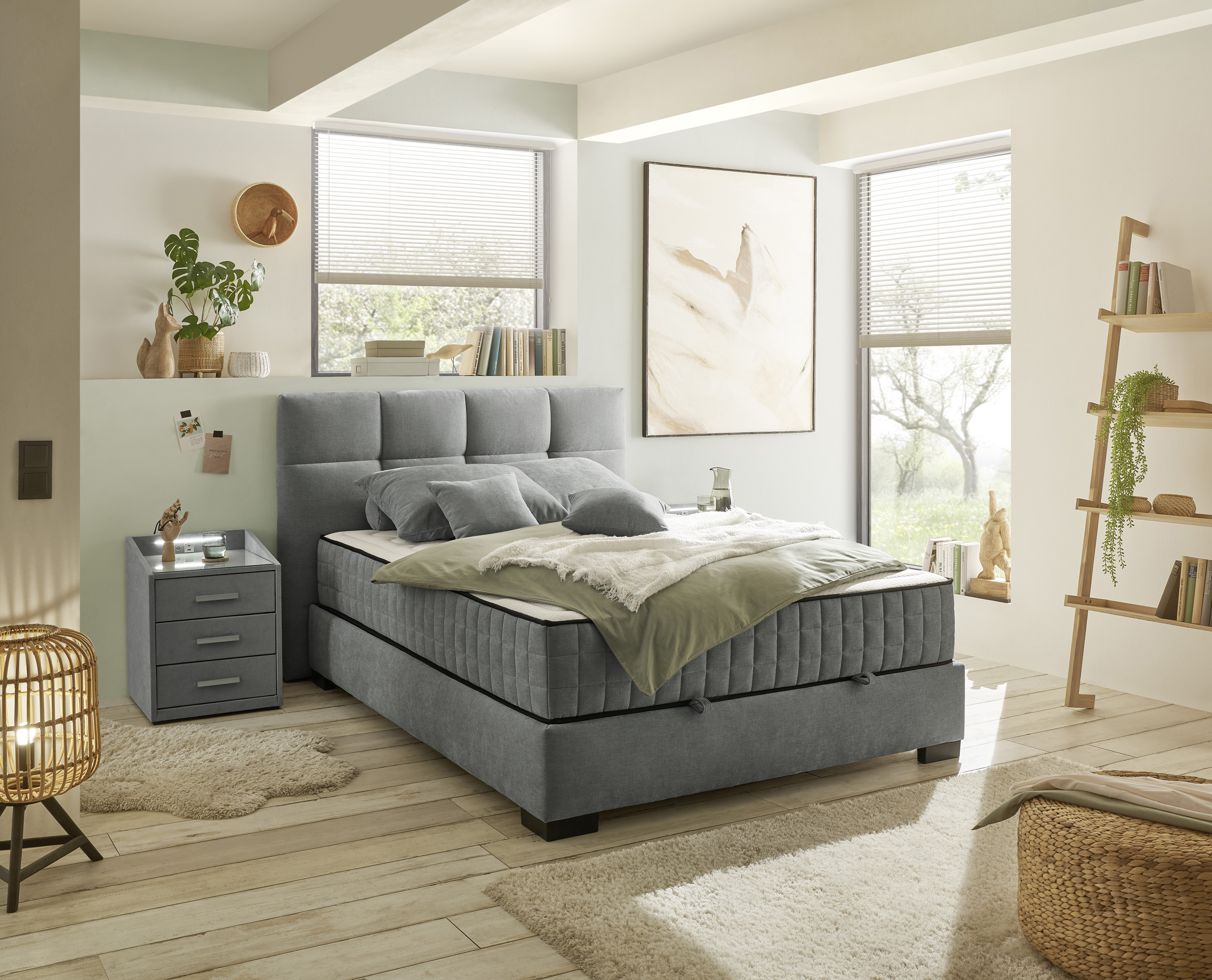 Boxspringbett „Wind 89 anthrazit“ in einem eingerichteten Schlafzimmer, dekoriert mit Kissen und Bettdecke, wohnliche Präsentation