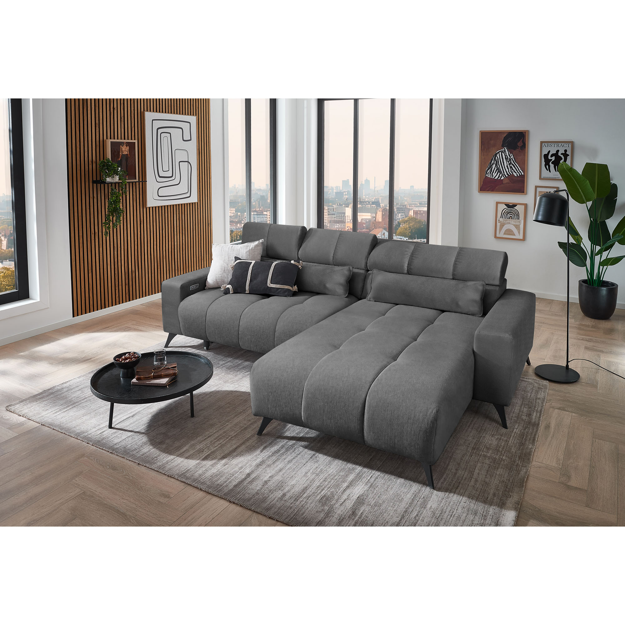 Dunkelgraues Ecksofa mit Ottomane rechts, verstellbaren Kopfstützen und Dekokissen in einem modern eingerichteten Wohnzimmer