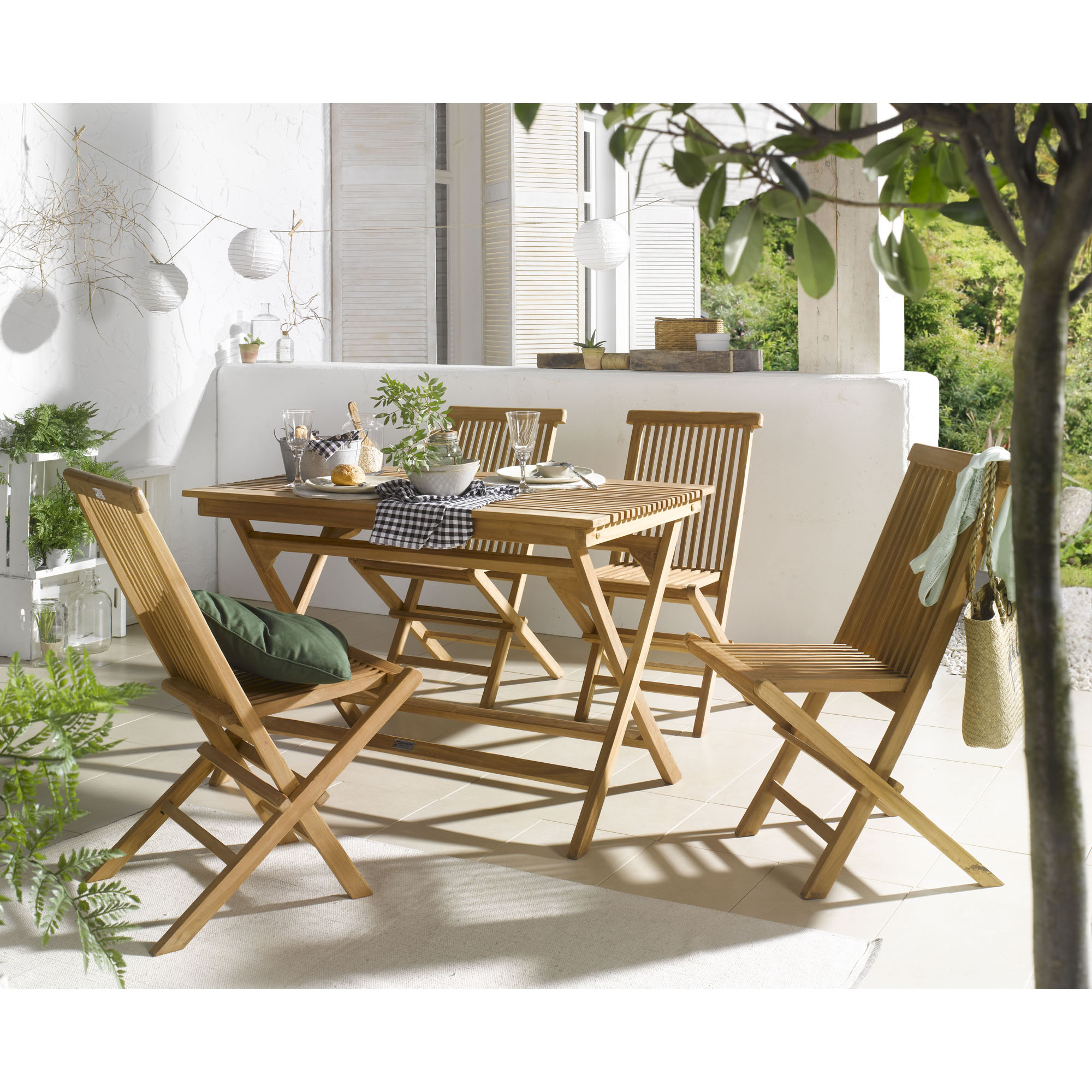 Holztisch aus Holz mit mehreren Klappstühlen auf einer Terrasse mit Pflanzen