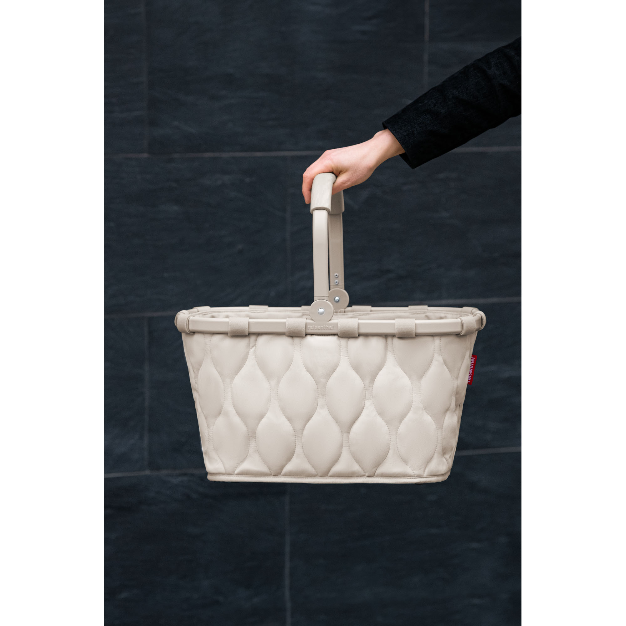 Einkaufskorb von Reisenthel, Modell Carrybag, in hellem Steinbeige mit Steppstruktur, von einer Person am Tragegriff getragen