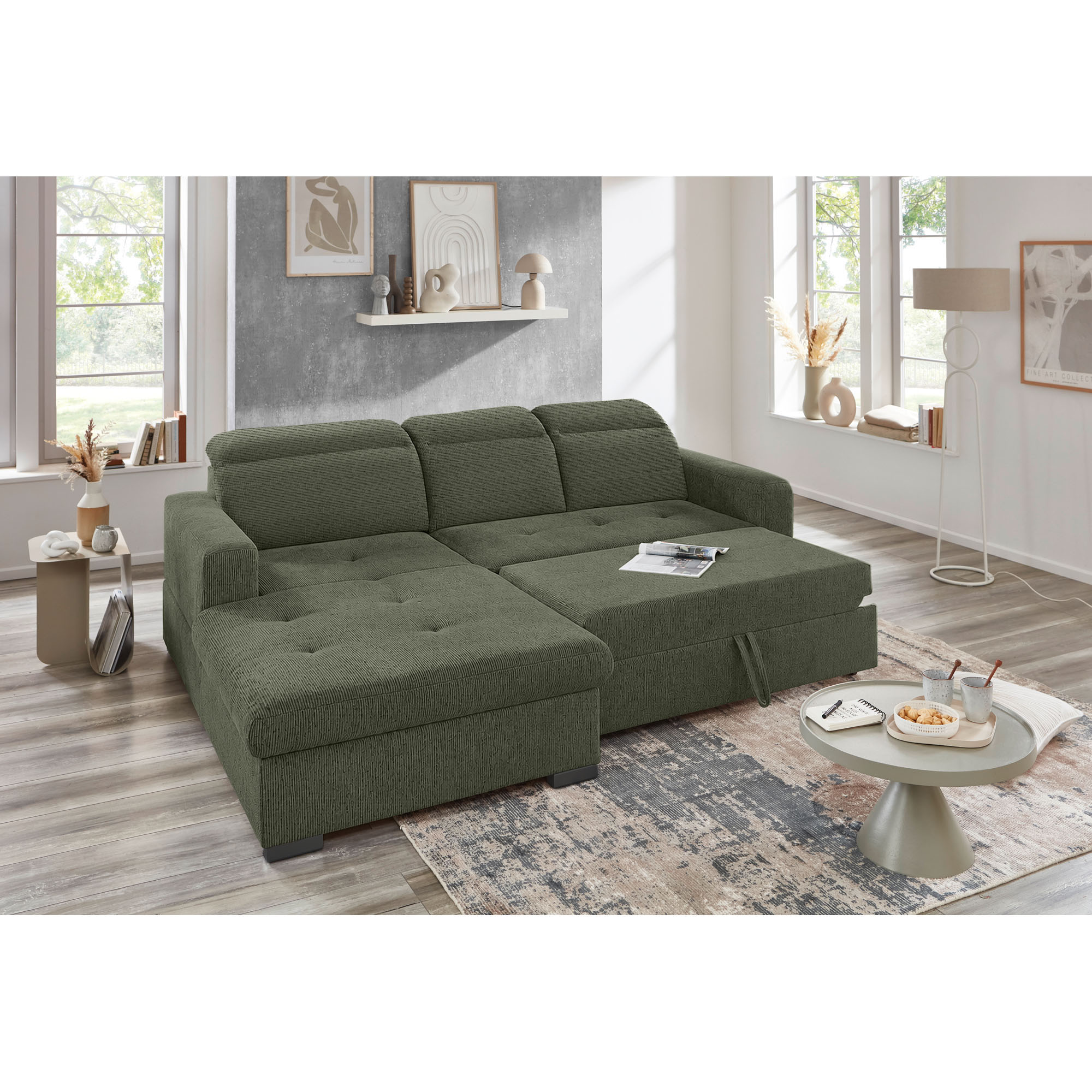 Grünes Ecksofa mit Ottomane links und ausgezogener Schlaffunktion in einem modern eingerichteten Wohnzimmer