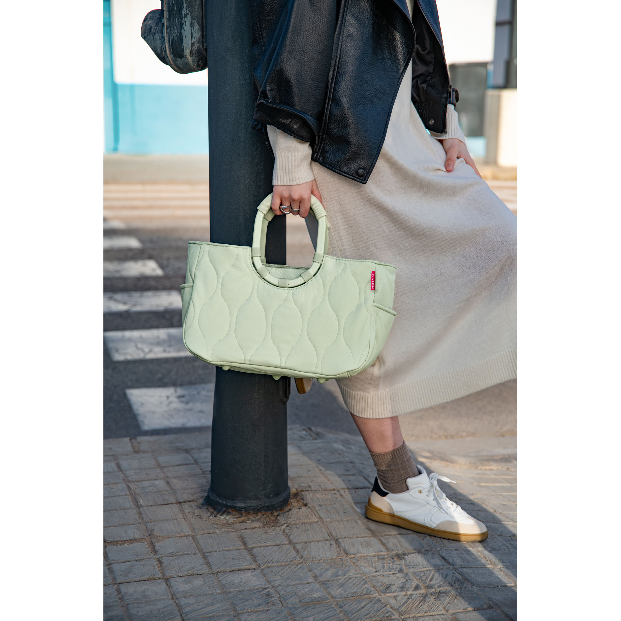 Shopper mit Ringgriffen von Reisenthel, Modell Loopshopper M, in Hellgrün mit Steppstruktur, von einer Person an den ovalen Ringgriffen getragen