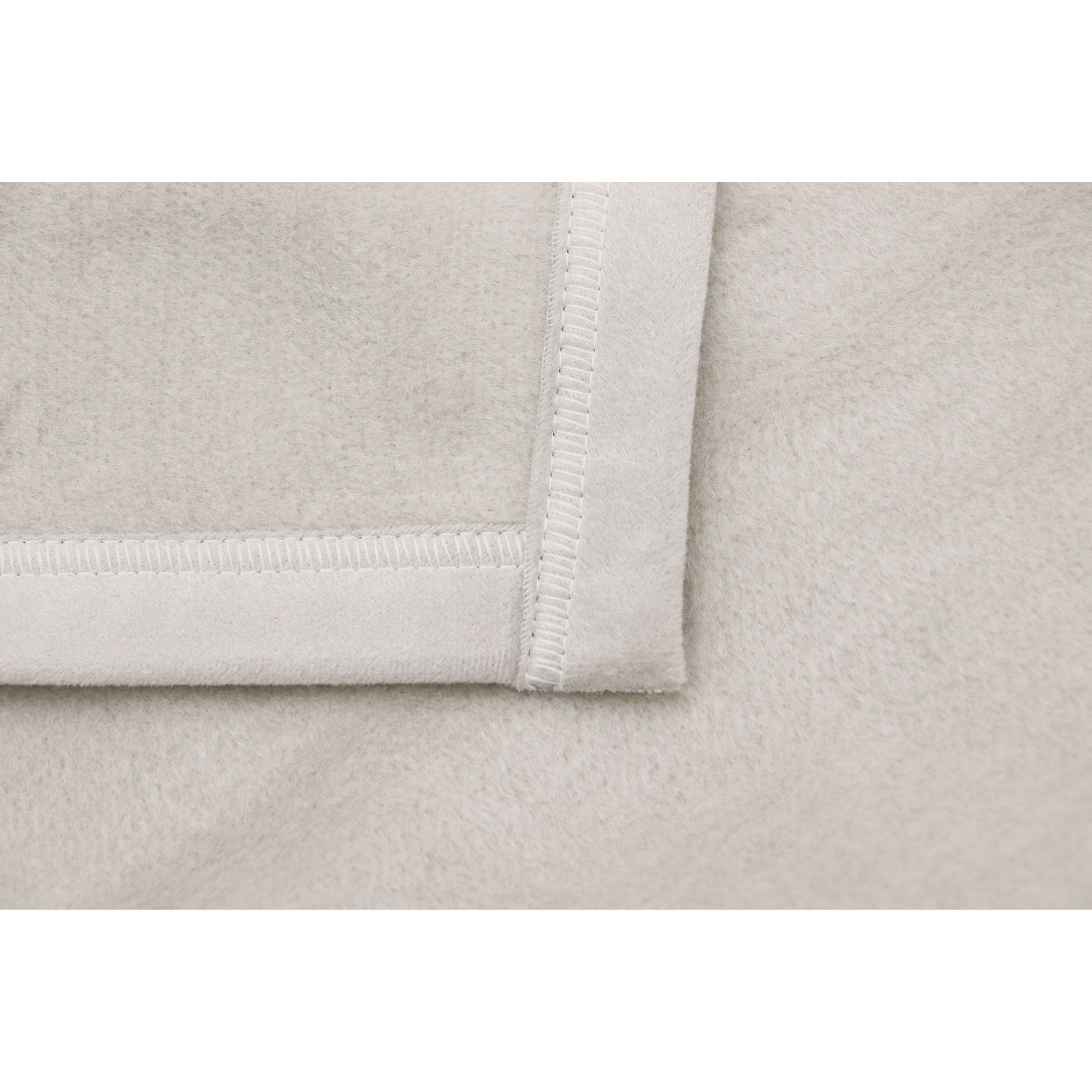 Detail der Wohndecke CottonSense silber mit geradem, hell eingefasstem Saum auf hellgrauem Stoff.