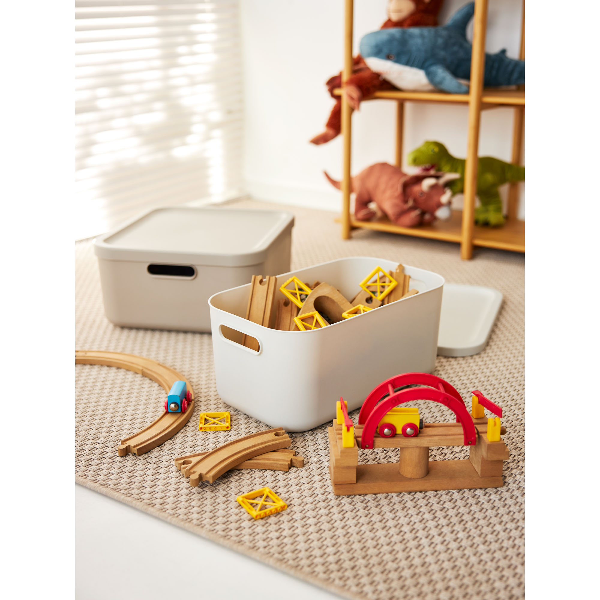 Mehrere beige Aufbewahrungsboxen mit Deckeln zur Aufbewahrung von Spielzeug in einem Kinderzimmer