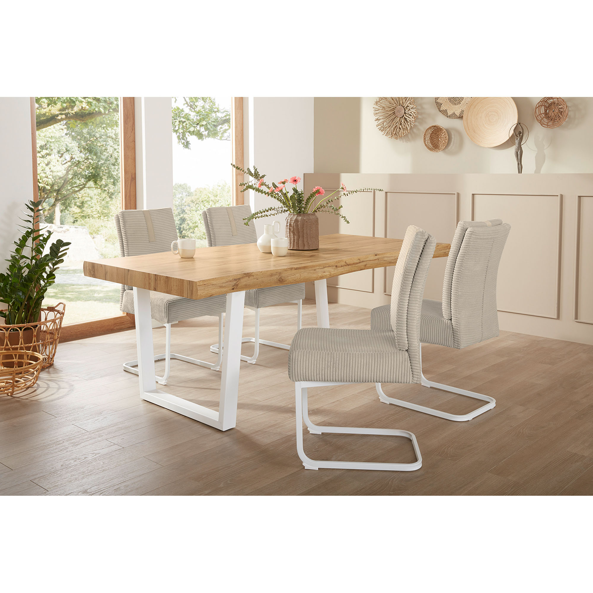 Helles Esszimmer mit großem Esstisch aus Holz und weißen Metallbeinen, dekoriert mit Stühlen und Accessoires.
