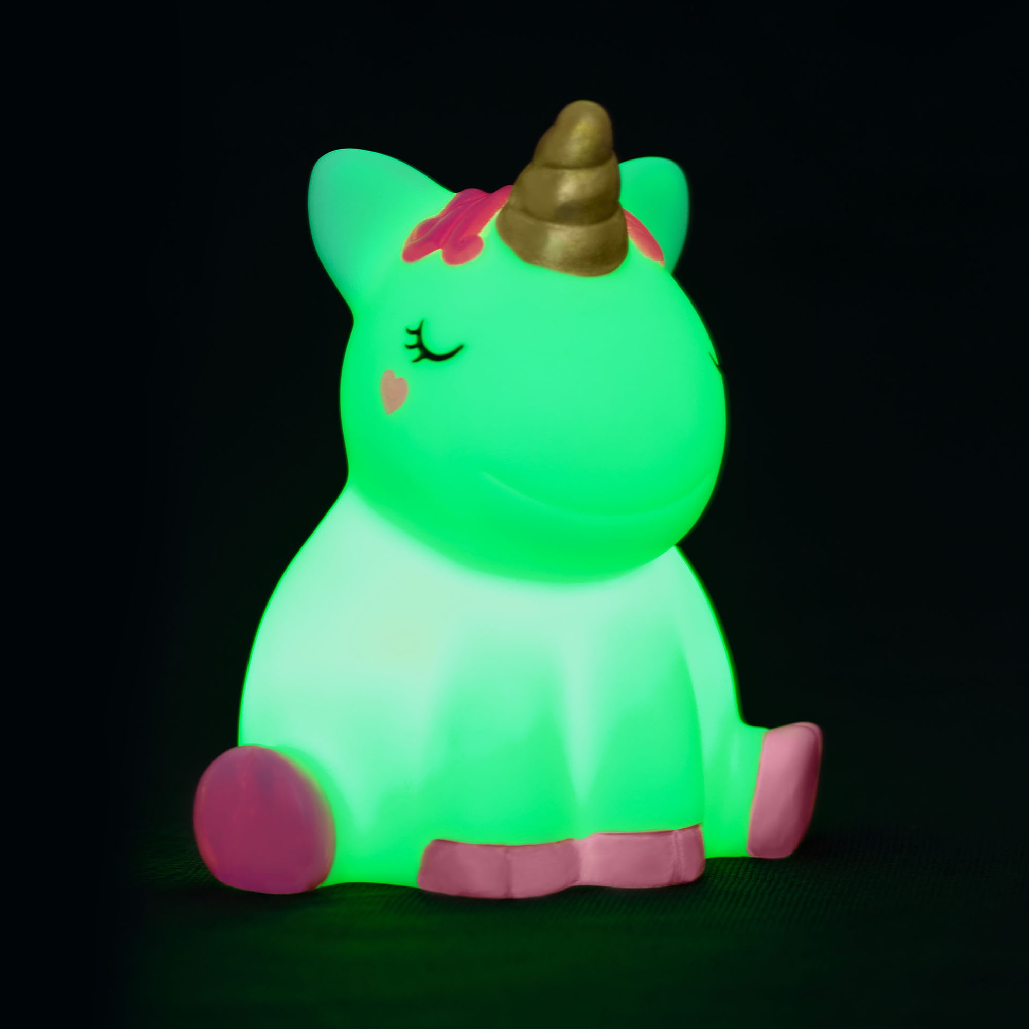 Nachtlicht in Einhornform, vor schwarzem Hintergrund grün leuchtend gezeigt.