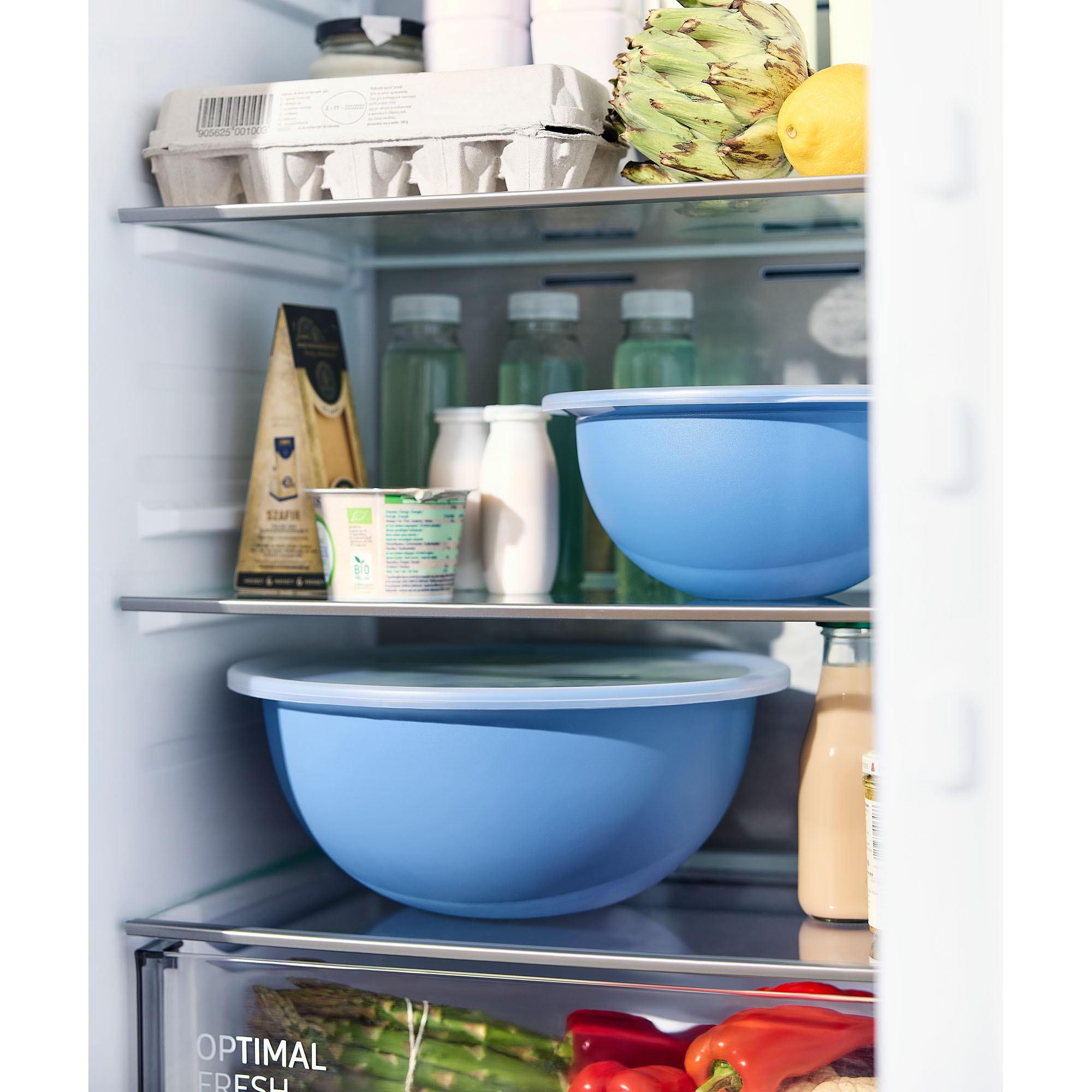 Blaue Rührschüsseln mit transparentem Deckel auf Ablagen in einem Kühlschrank