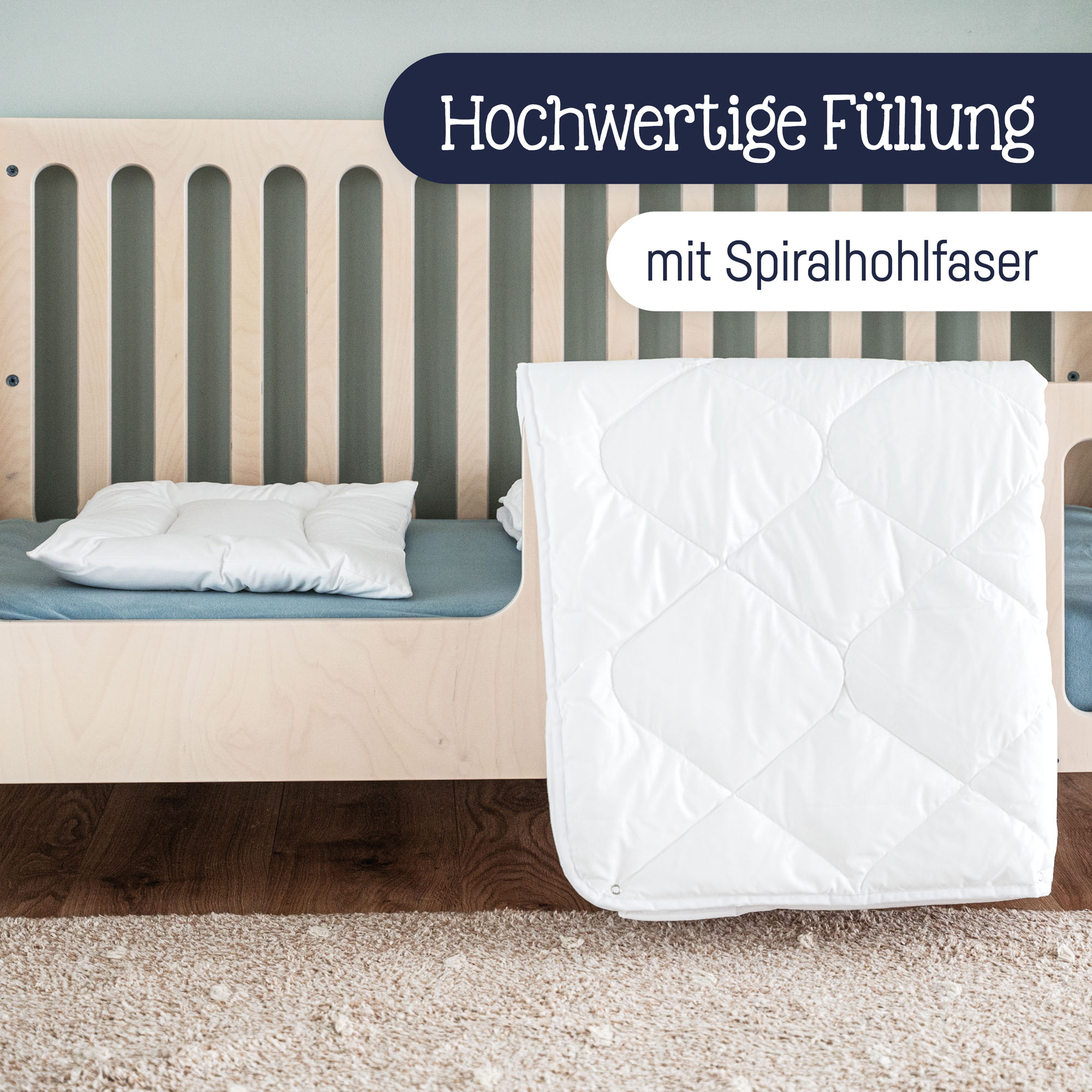 Weiße Steppdecke über Bettkante gehängt und weißes Kissen im Kinderbett mit Holzrahmen platziert