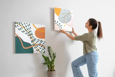 Junge Gestalterin für visuelles Marketing hängt Art-Deko-Bilder in der Ausstellung von Möbel Gruber auf