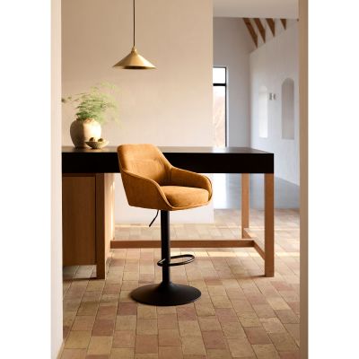 Gepolsterter Barhocker mit senfgelbem Bezug und schwarzem Gestell, platziert an einem dunklen Bartisch in modernem Raum