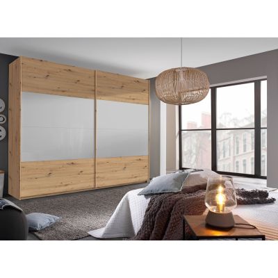 Schwebetürenschrank in Eiche Artisan mit Front in Seidengrau, in Schrägansicht in einem Schlafzimmer-Milieu gezeigt.